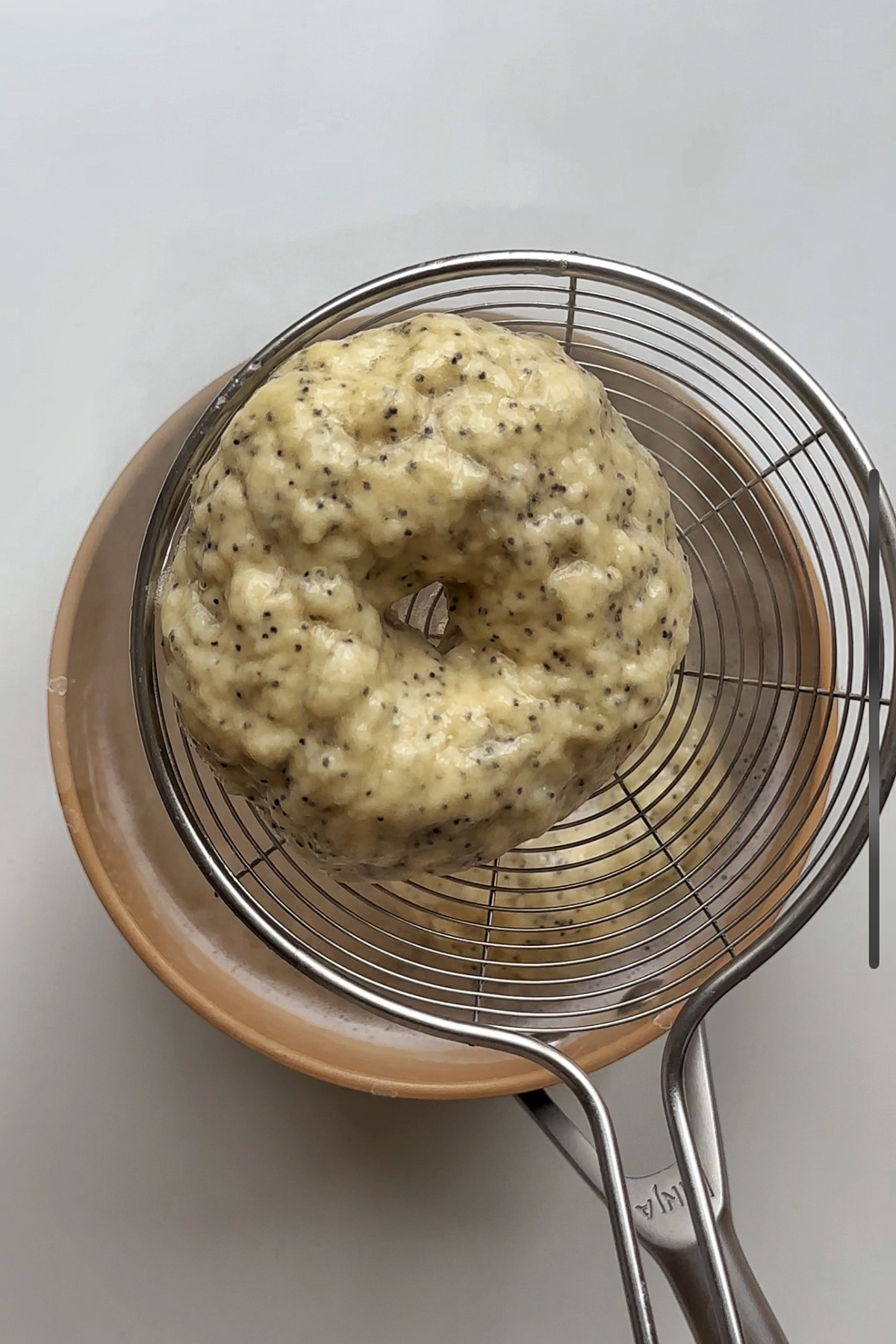 Boiled bagels being plucked out of the water.