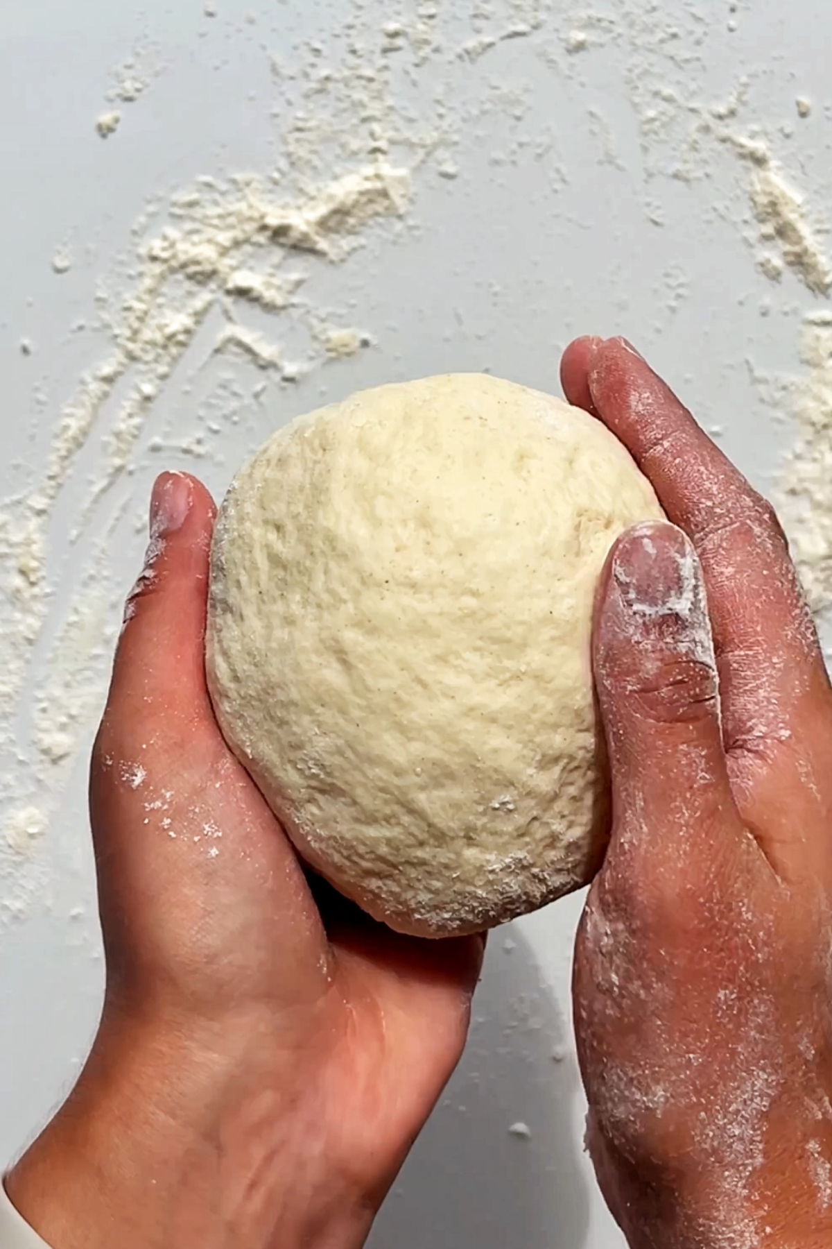 Holding a ball of dough in hands.