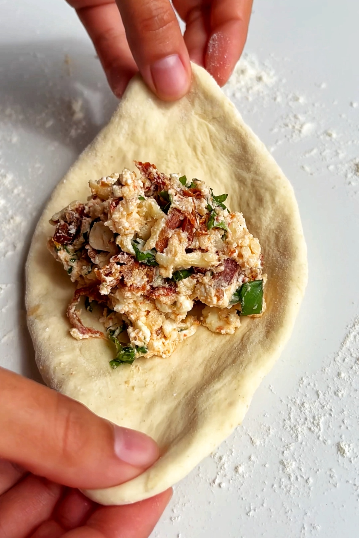 Caprese flatbread filling inside of dough being wrapped up around it.
