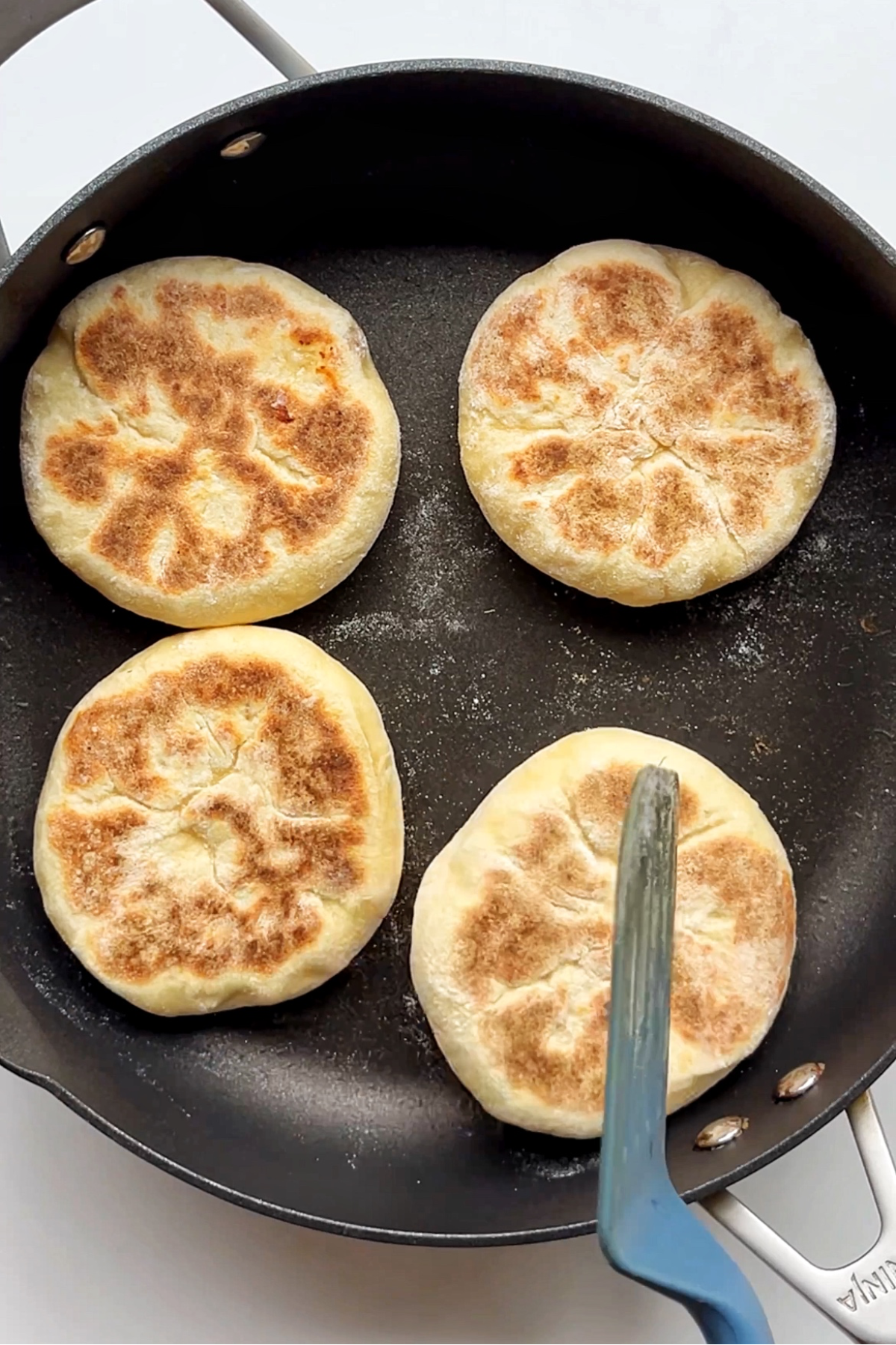Flatbreads being dry fried in a frying pan.