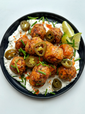 Plate of air fryer chicken meatballs with buffalo sauce and blue sauce.