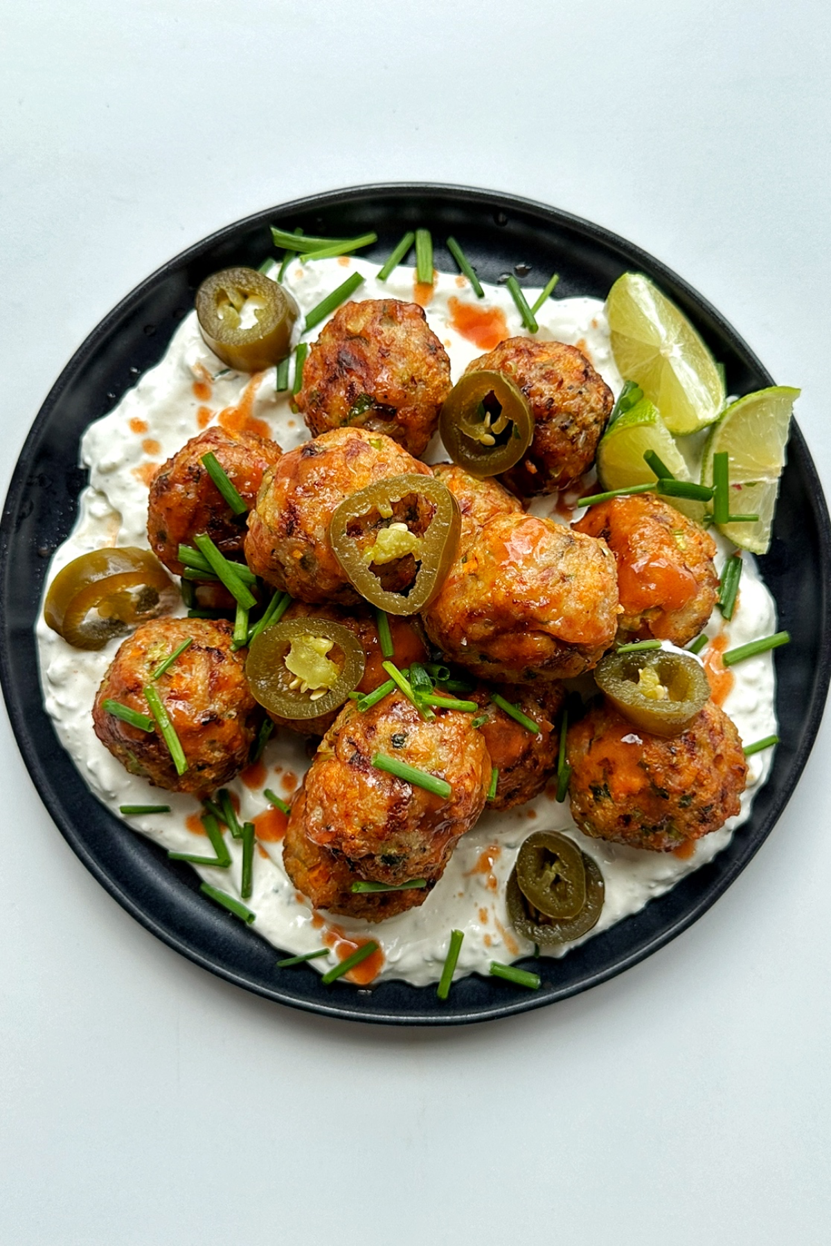 Plate of air fryer chicken meatballs with buffalo sauce and blue sauce.