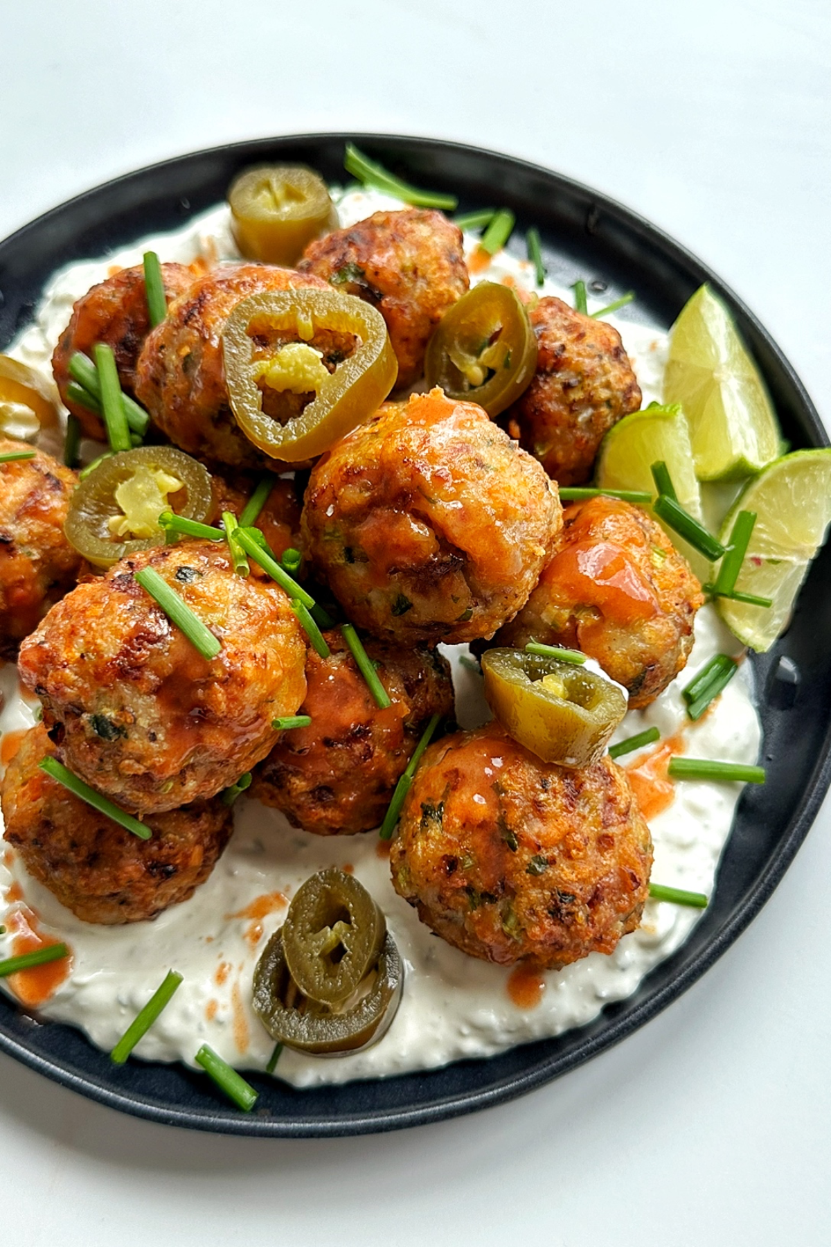 Close up of air fryer chicken meatballs coated in buffalo sauce and served with homemade blue cheese sauce.