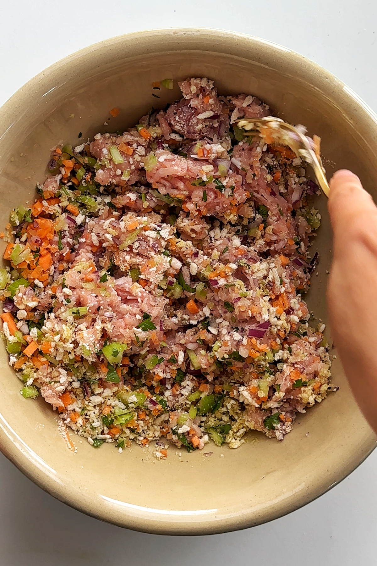 Combining chicken meatball ingredients in a large bowl.
