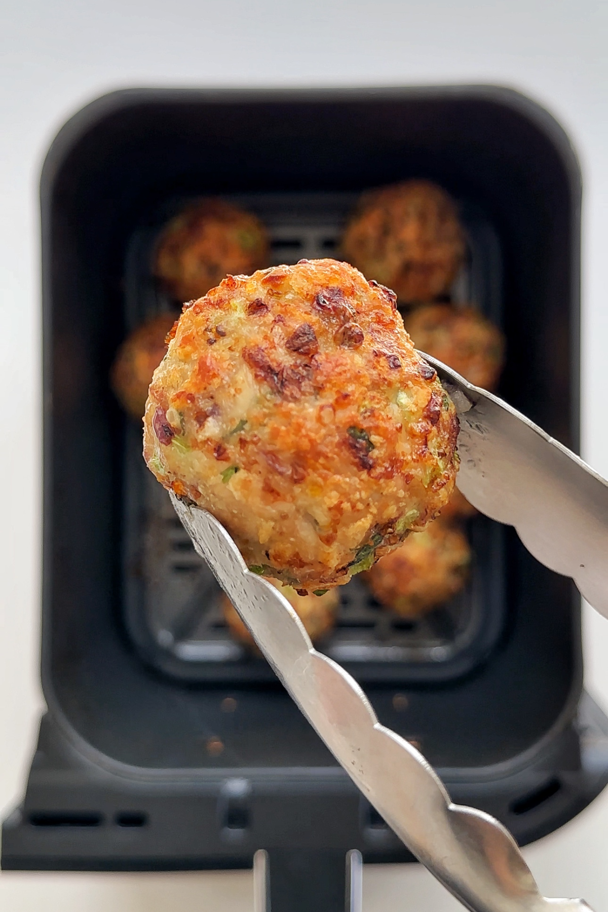 Holding up an air fryer chicken meatball that has been freshly cooked.