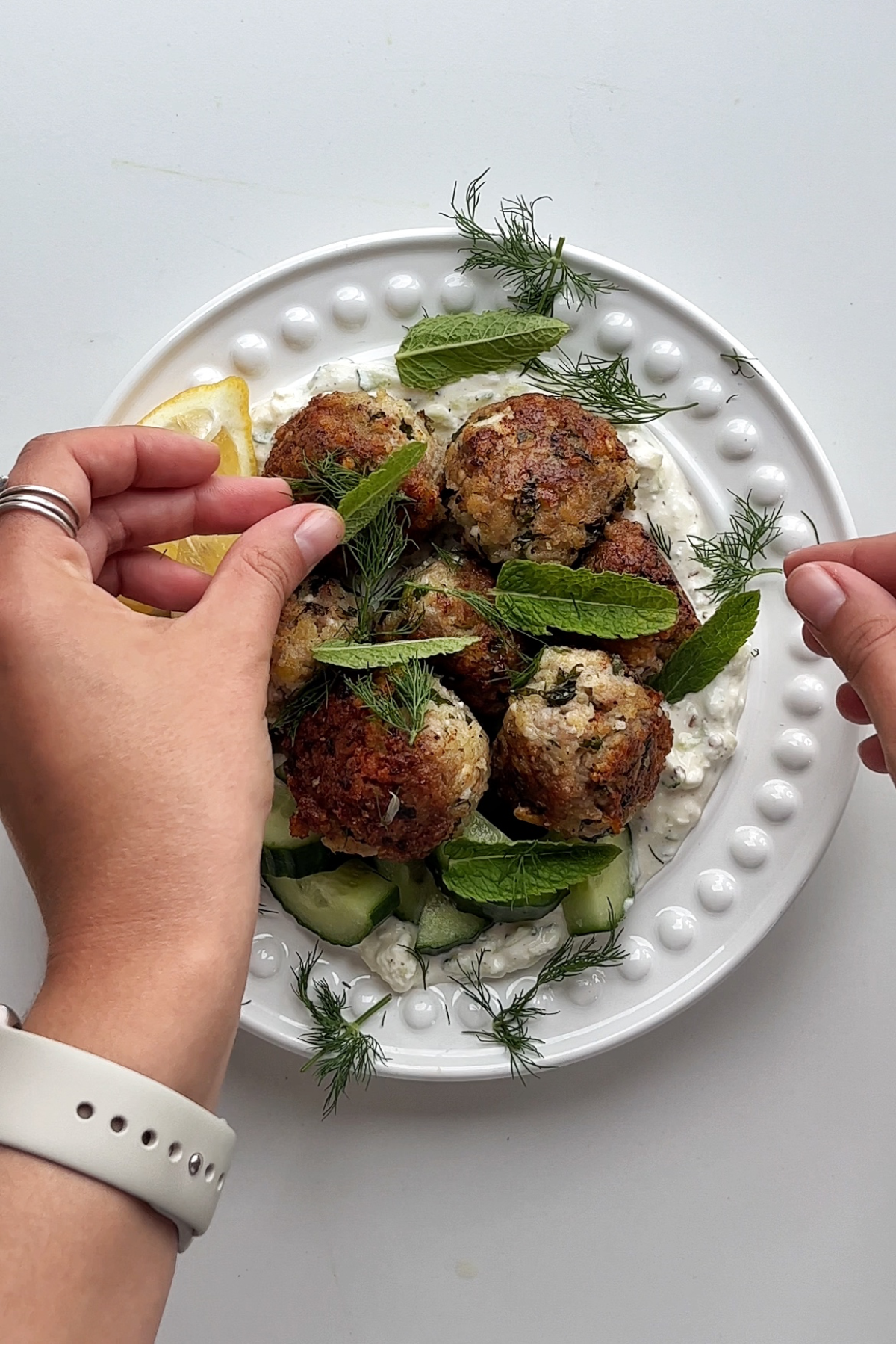 Plating up Greek meatballs aka keftedes on a white plate.