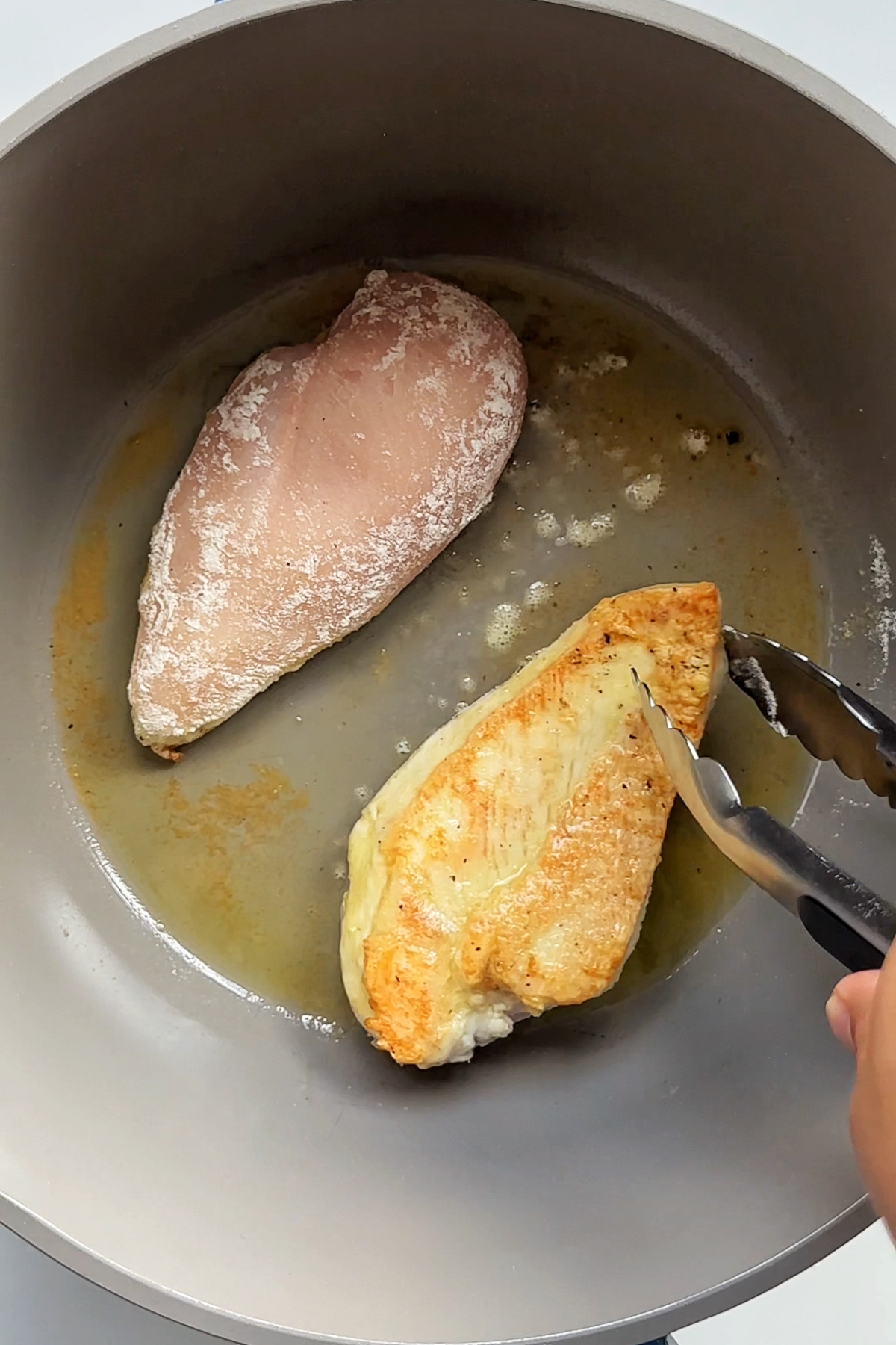 Searing chicken breast in a saucepan. 