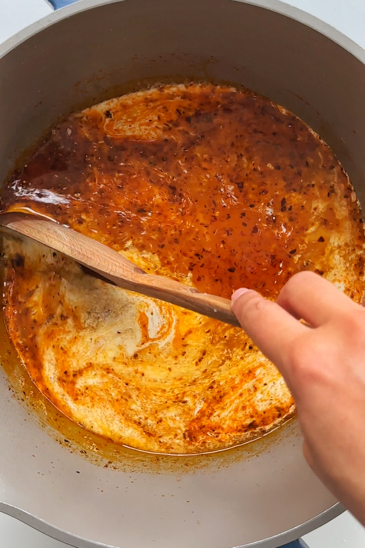 Stirring a pot of cream and chicken stock in a sauce pan to make lemon chicken ramen. 