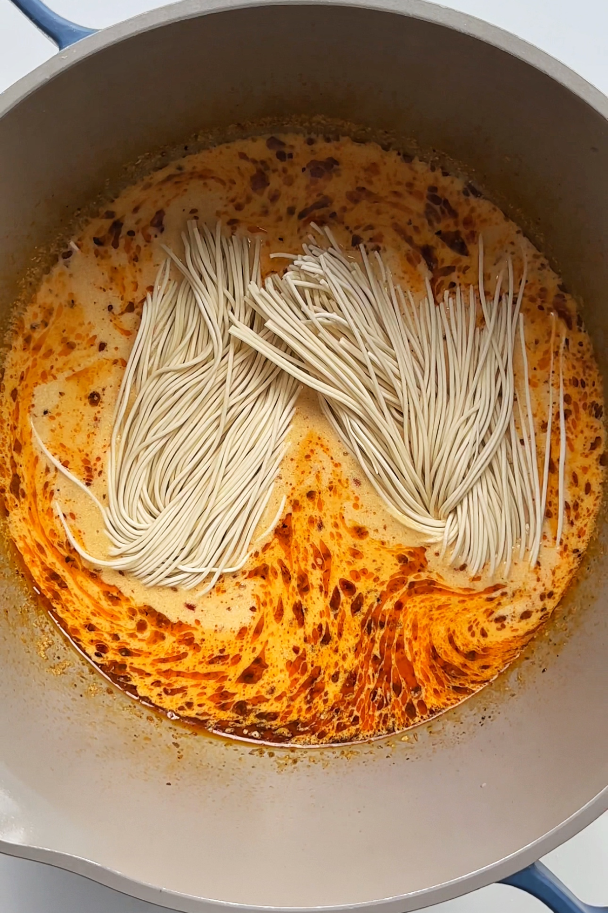 Placing ramen noodles into a lemon chicken ramen broth. 