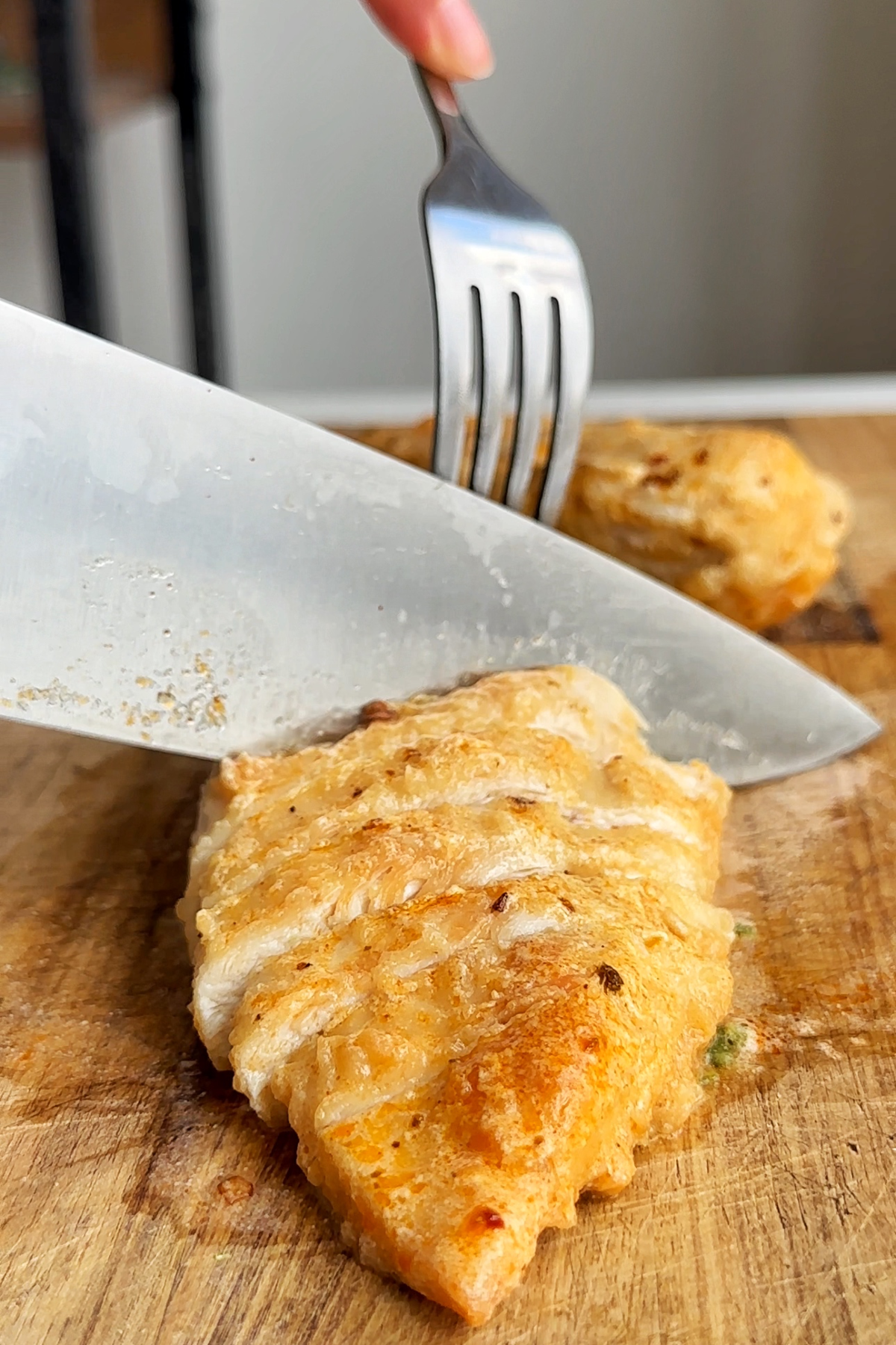 Slicing chicken breast on a chopping board. 