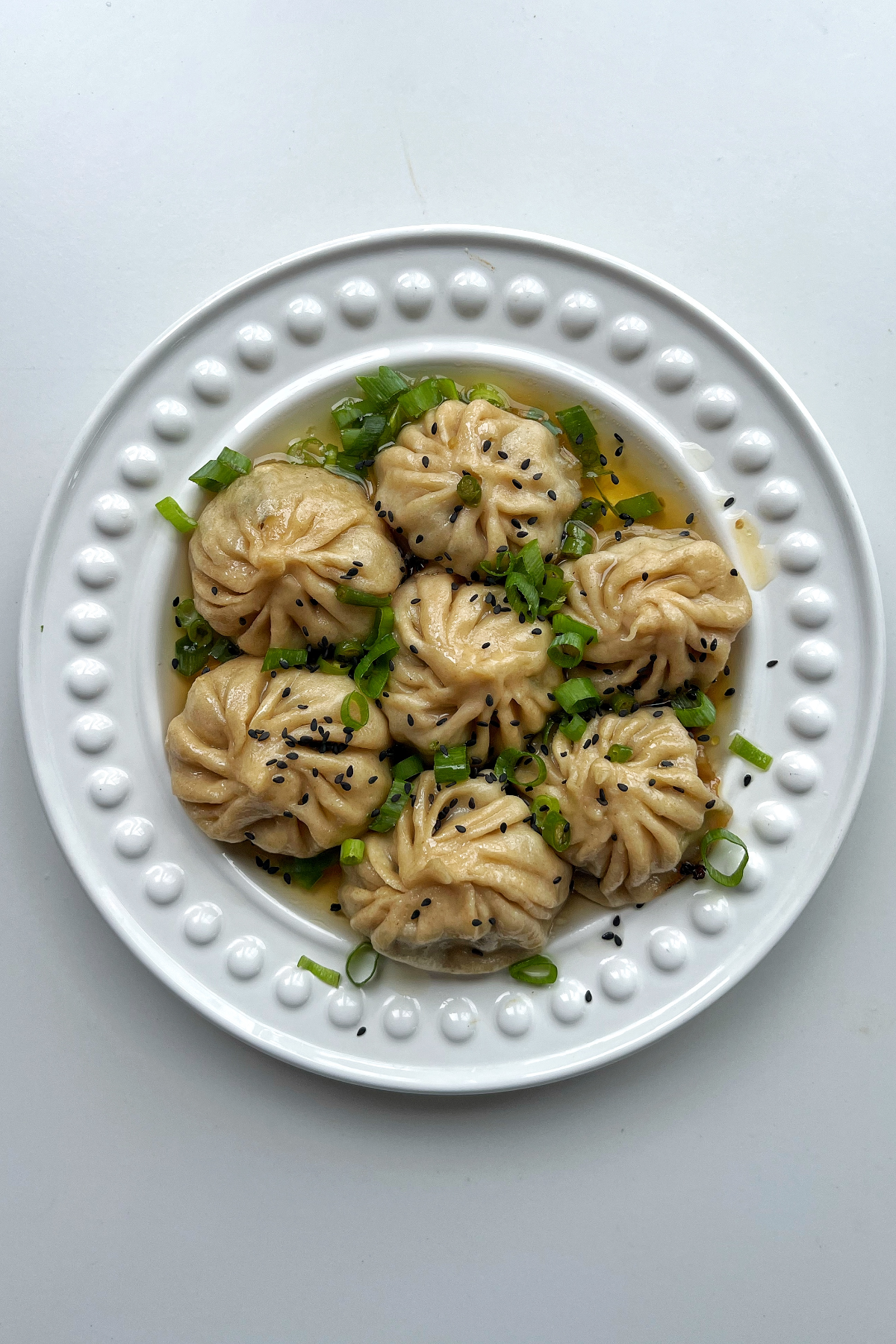 Pan fried lemongrass and beef dumplings on a white plate.