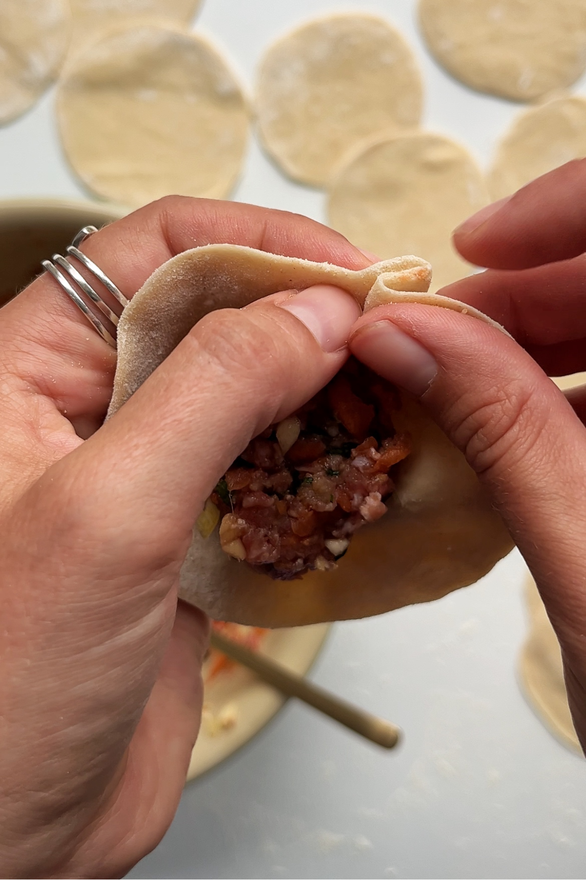 Folding up a dumpling in a clockwise motion.