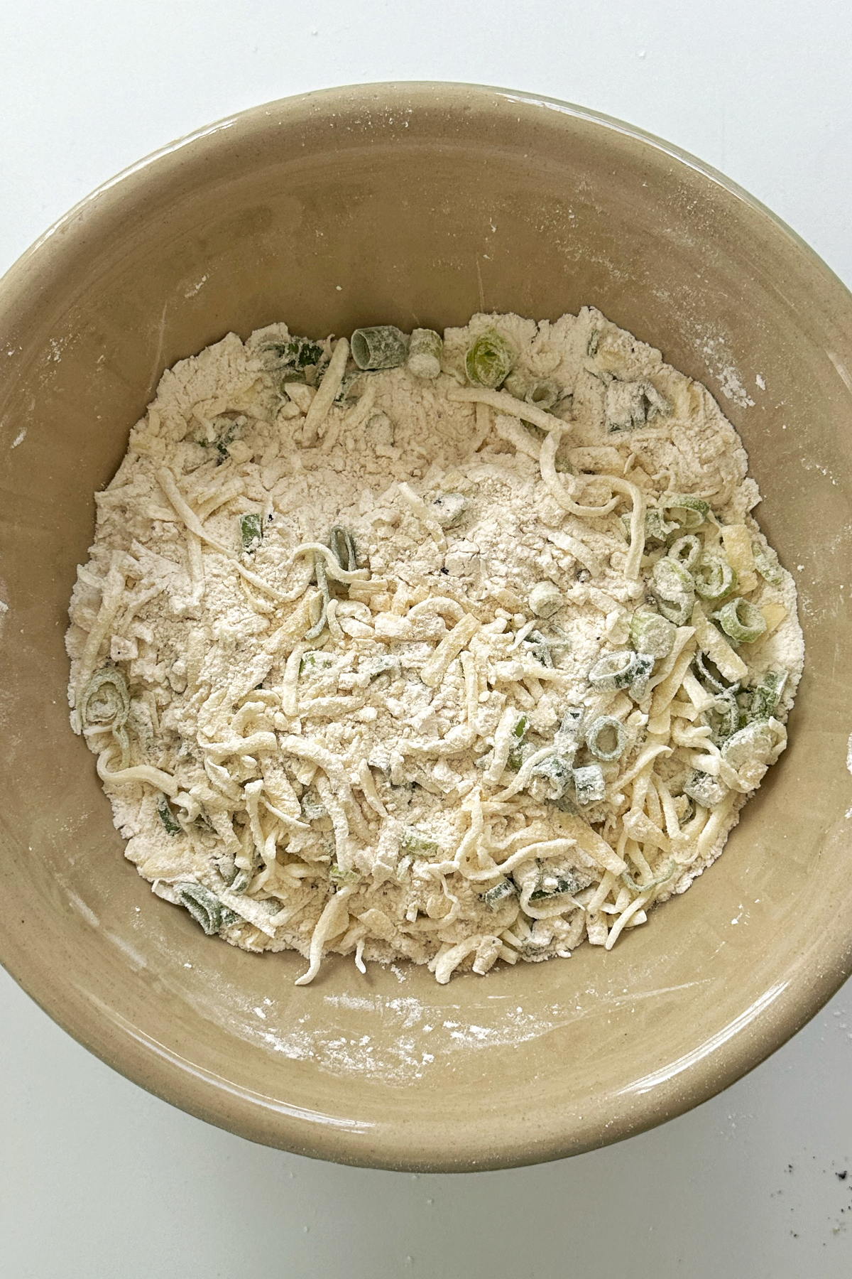 Combining the dry ingredients for cheese bacon muffins in a bowl.