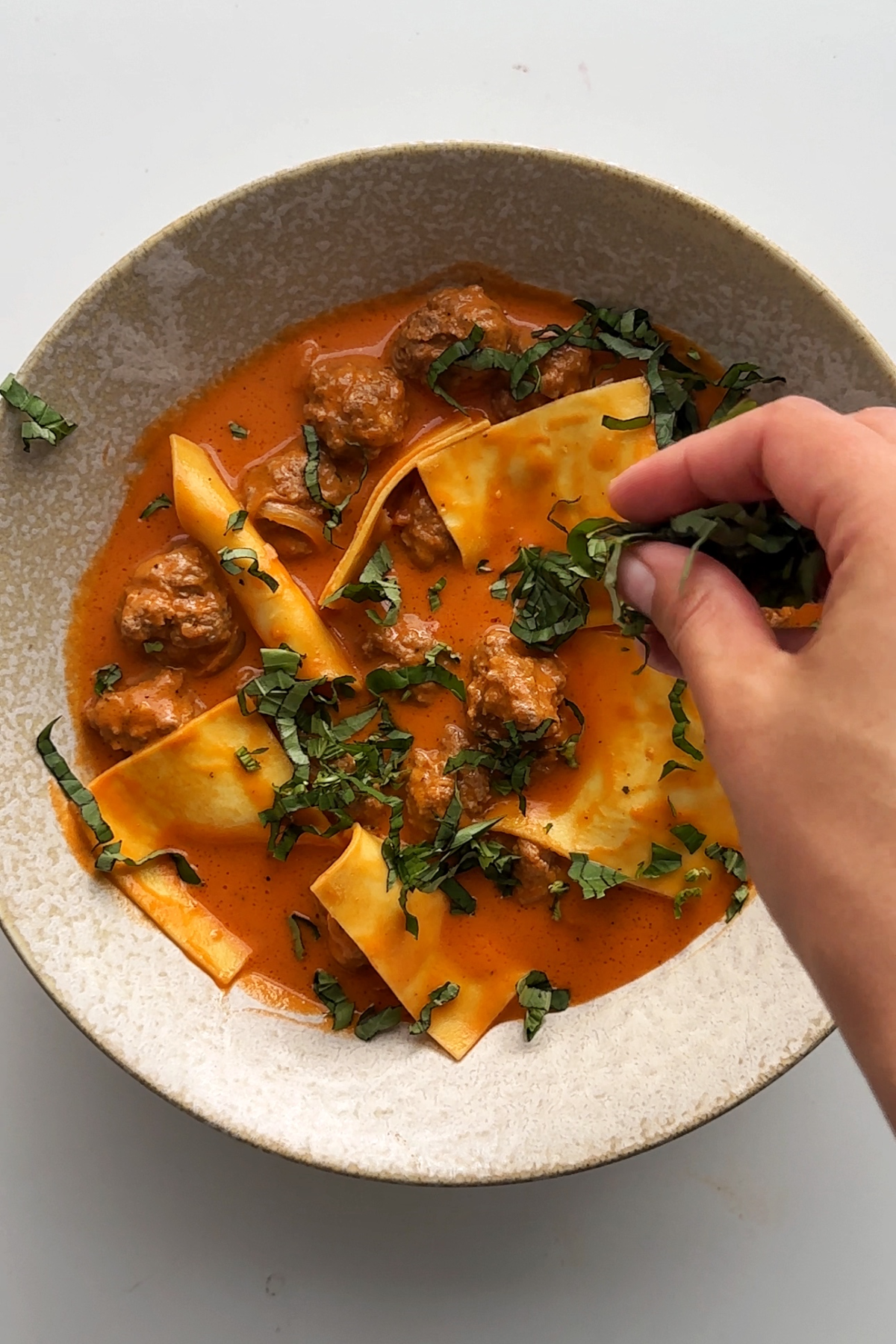 Garnishing the deconstructed ravioli soup with fresh basil.
