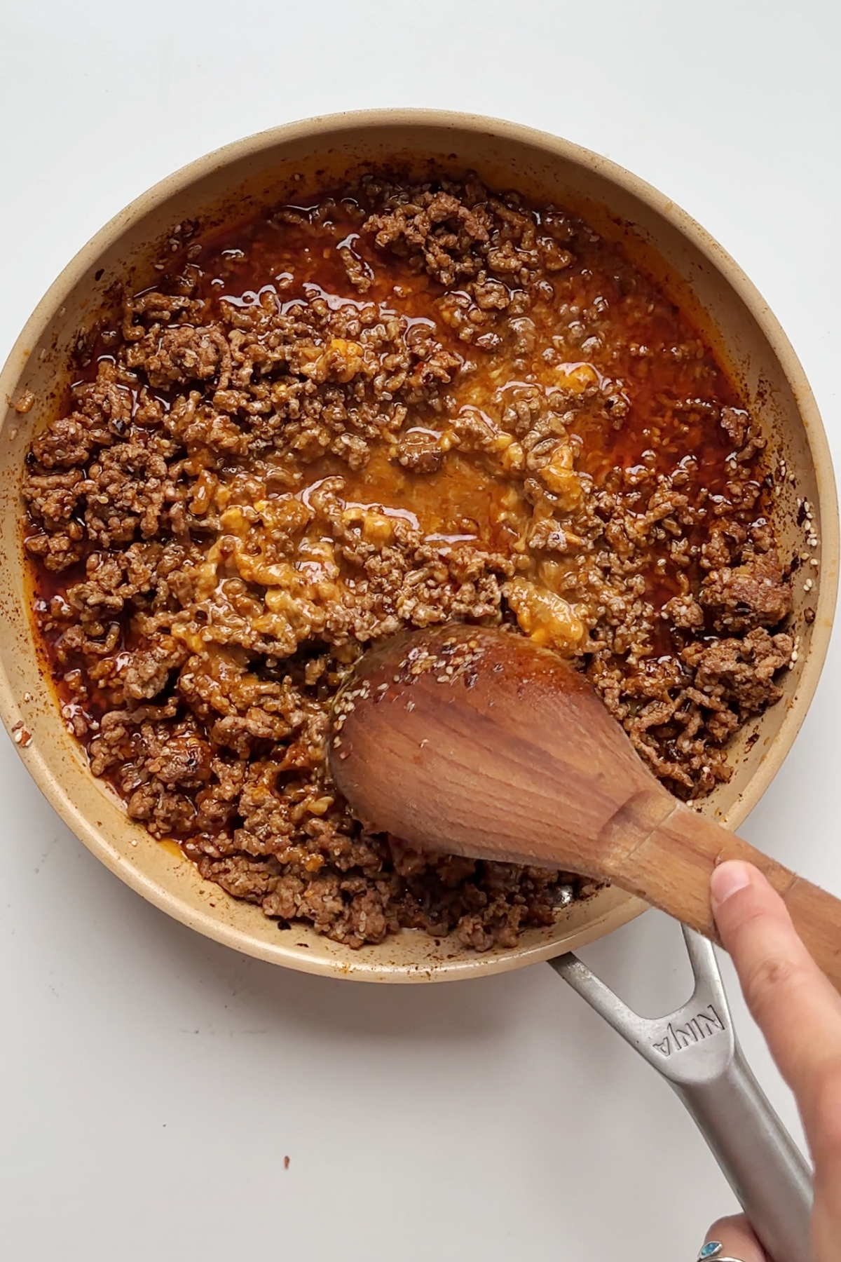 Stirring fried beef with a sauce in a frying pan.