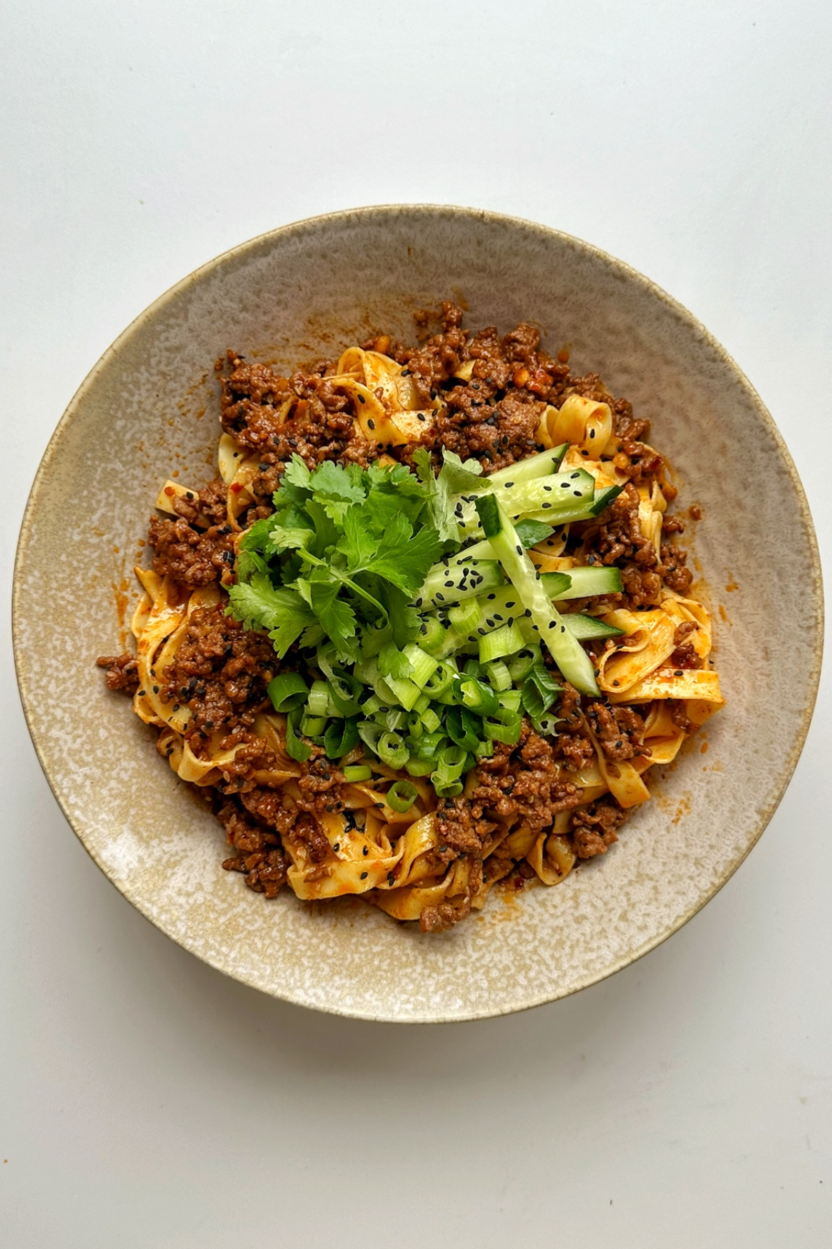 Egg noodles with ground beef topped with cilantro, cucumber, green onions.