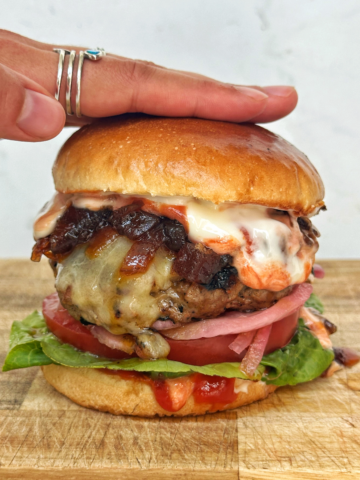 Hamburger patty in a bun with lettuce, tomato, onion.