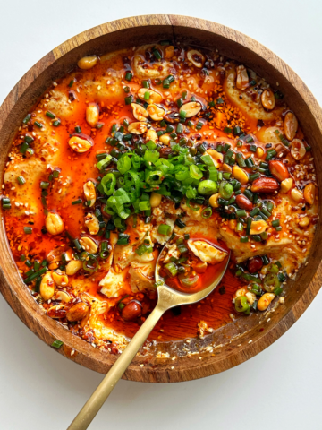 Steamed eggs recipe topped with chili oil, chives, and green onions.