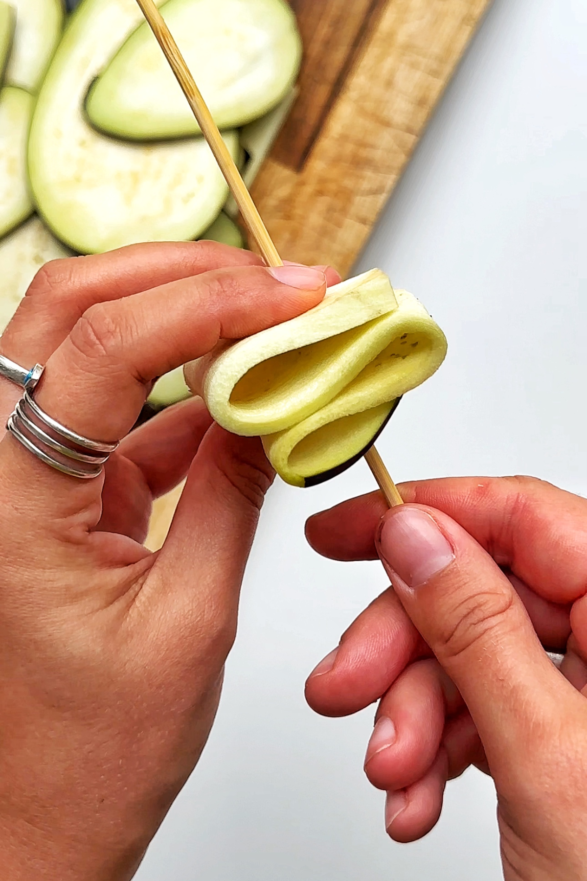Folding individual eggplant slices and placing them onto skewers.