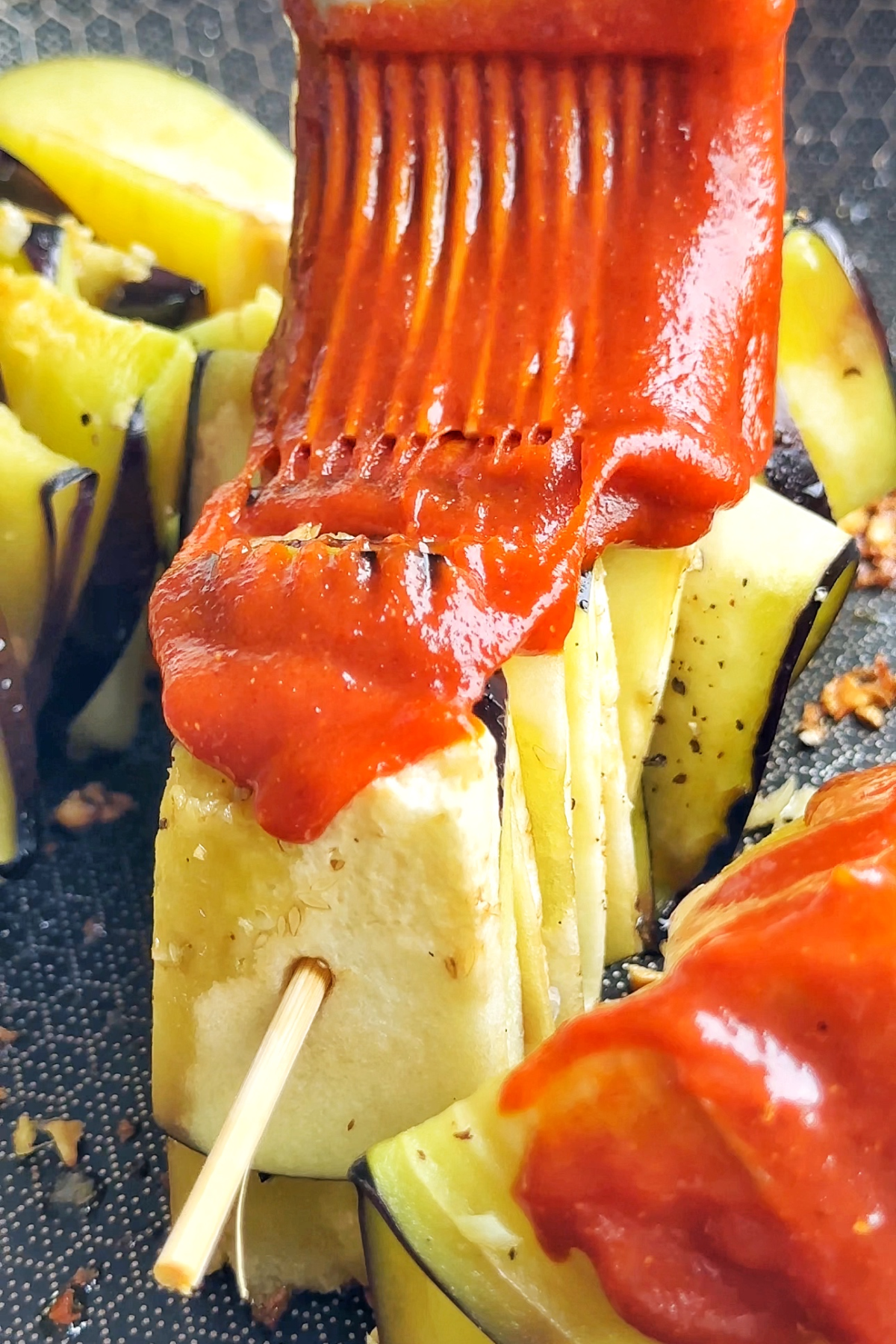 Brushing the sauce onto the eggplant skewers.