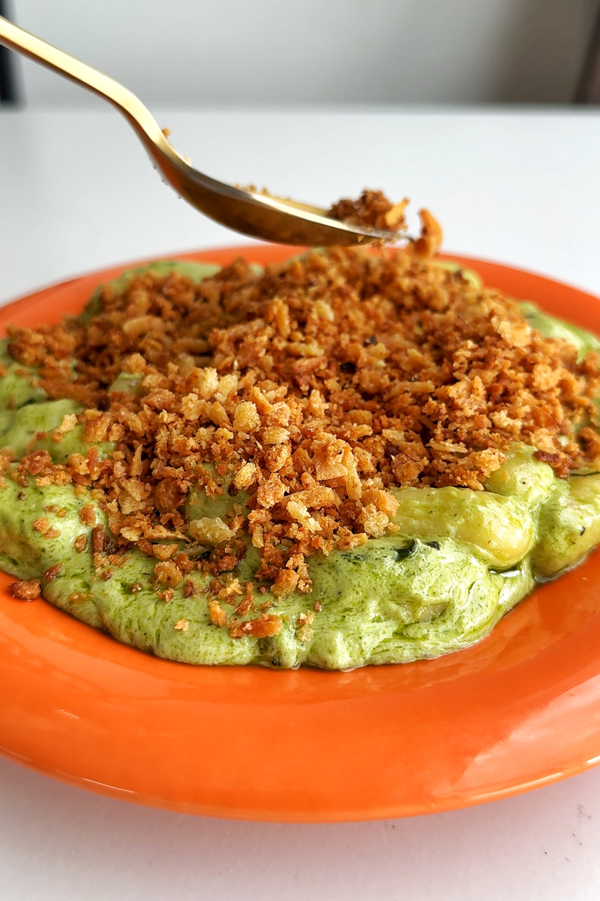 Sprinkling pangrattato onto pesto gnocchi.