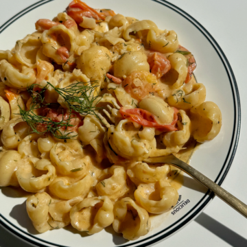 Goat cheese pasta with golden fork topped with dill and lemon zest.