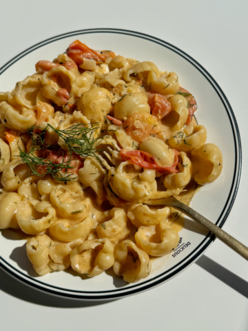 Goat cheese pasta with golden fork topped with dill and lemon zest.