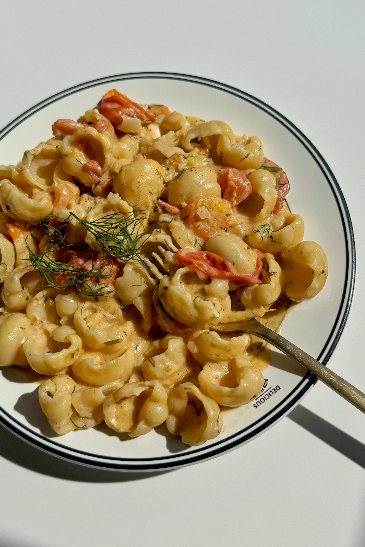 Goat cheese pasta with golden fork topped with dill and lemon zest.