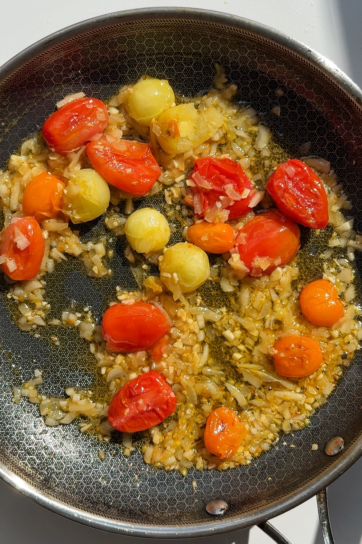 Frying garlic, onion, and tomatoes in a black skillet.