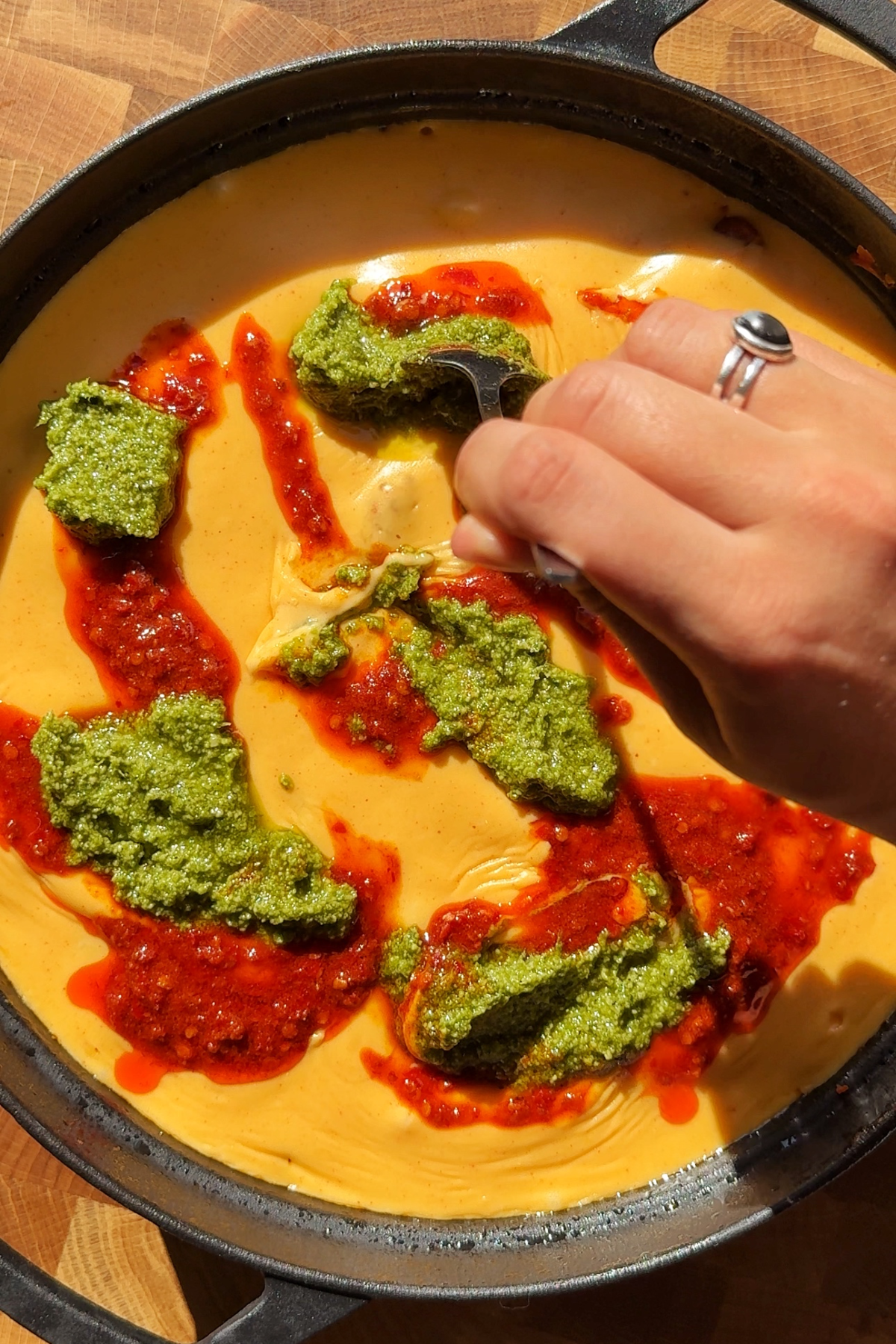 Adding nduja and fresh basil pesto onto the sweet potato and ground beef dish.