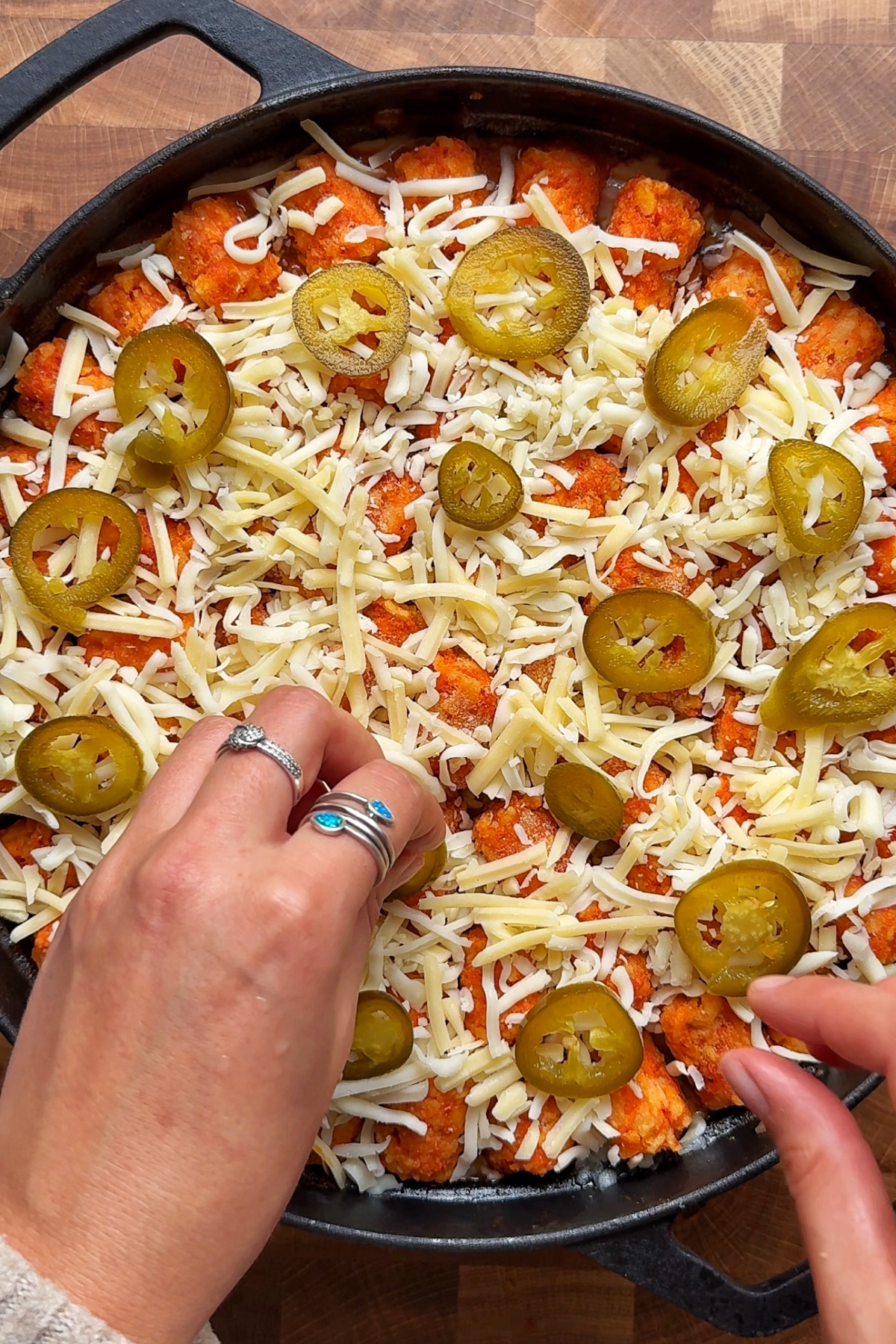 Sprinkling cheese and jalapeños over the cowboy casserole.