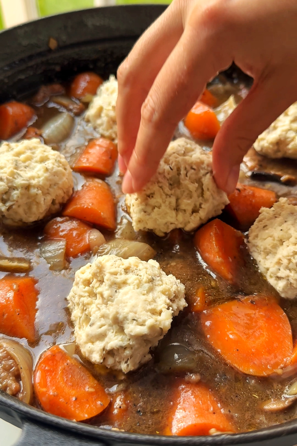 Placing herb dumplings on top of beef stew.