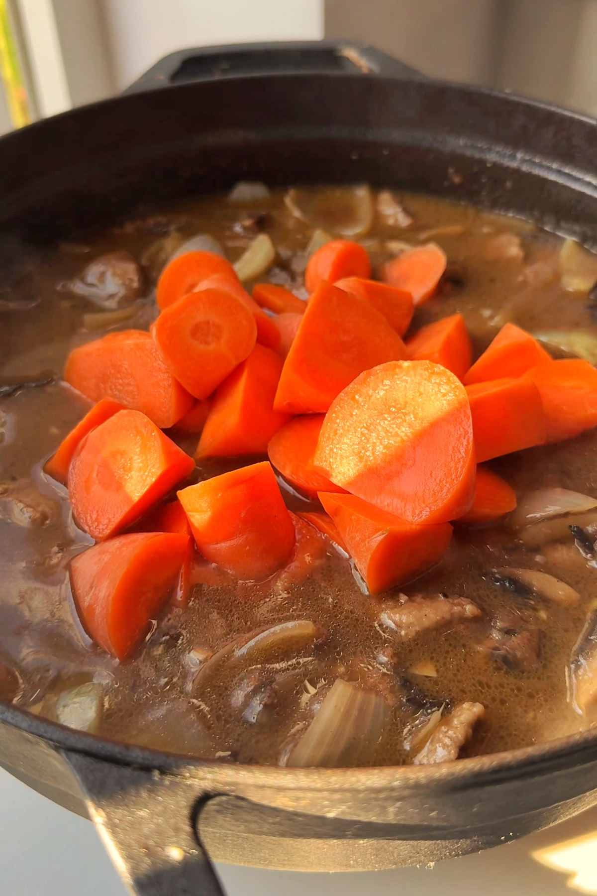 Adding carrots to beef stew.