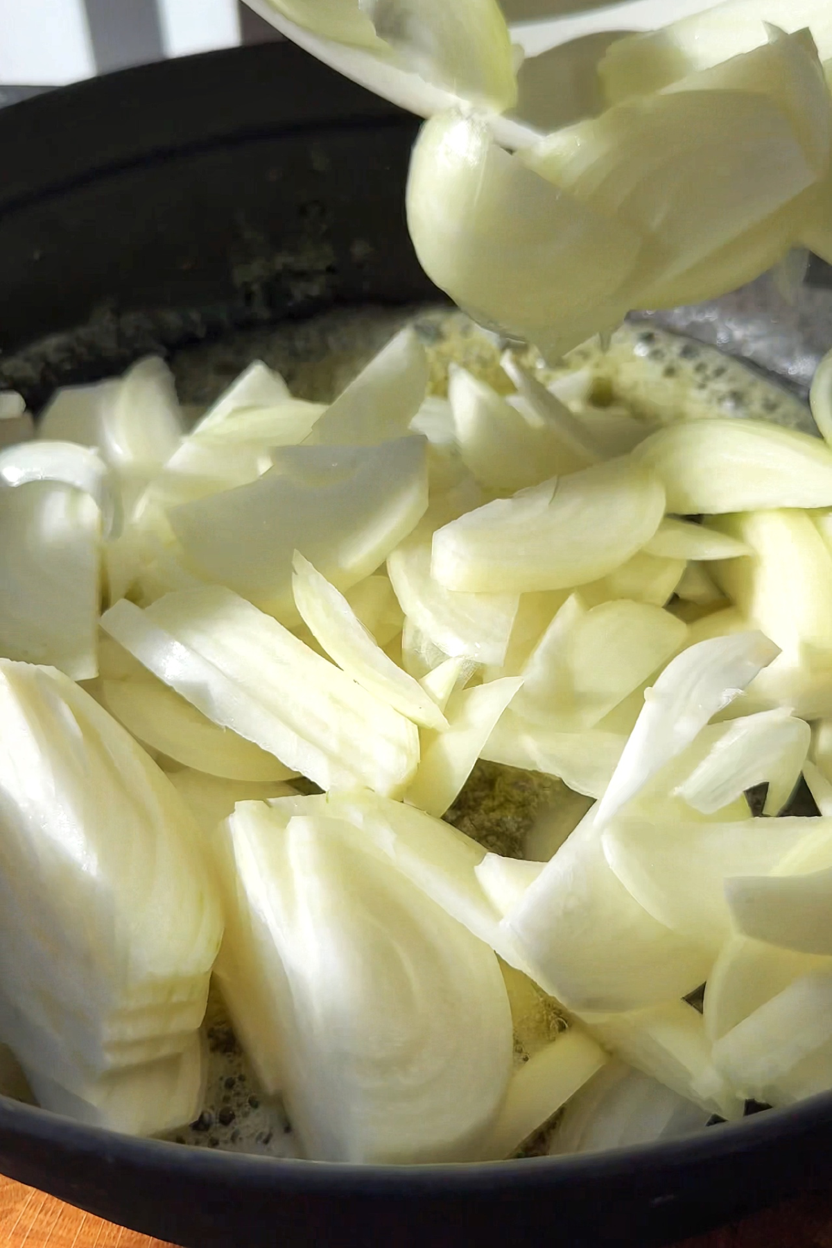White onions frying in a casserole dish.