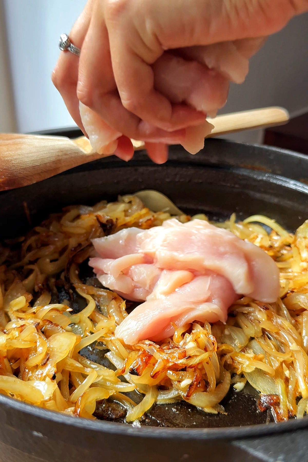 Adding chicken into the French onion soup chicken casserole dish.