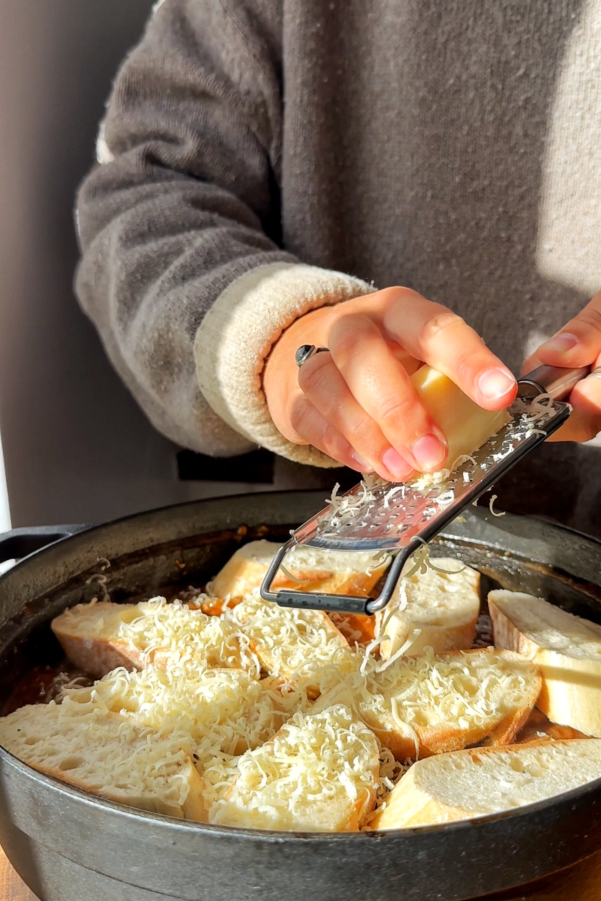 Grating gruyere onto the French onion chicken casserole.