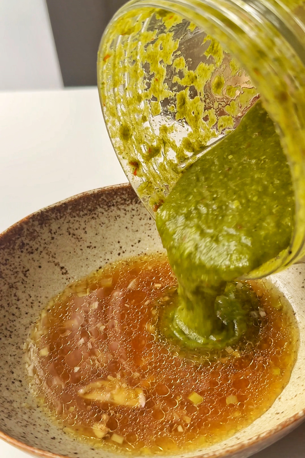 Pouring the coriander sauce into the chicken juices.
