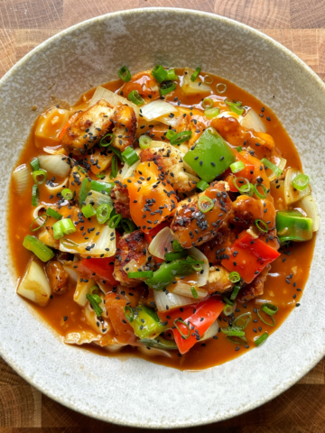 Sweet and sour chicken noodles in a white bowl.