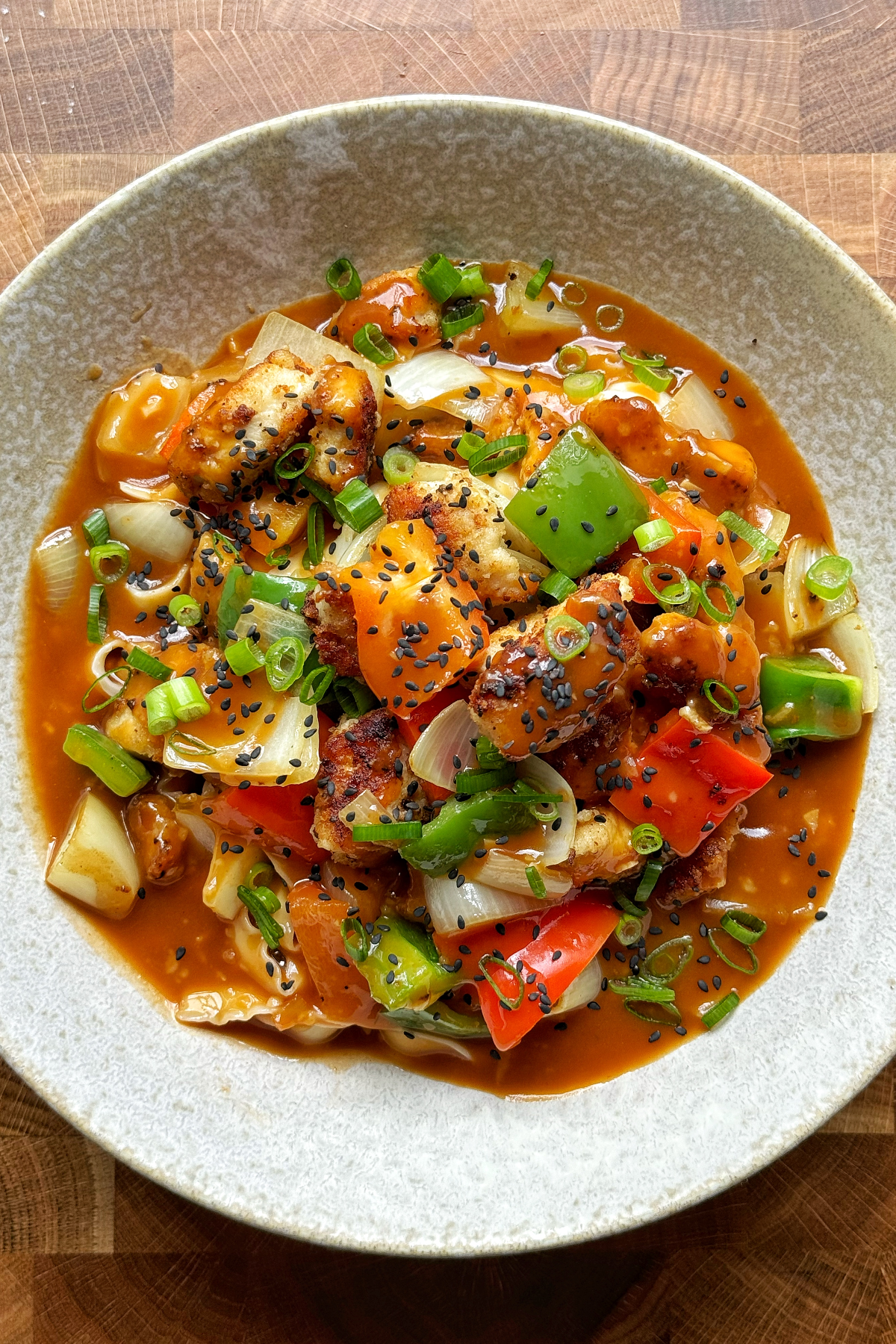 Sweet and sour chicken noodles in a white bowl.