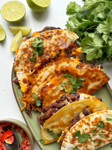Bean tacos stacked on a green platter.