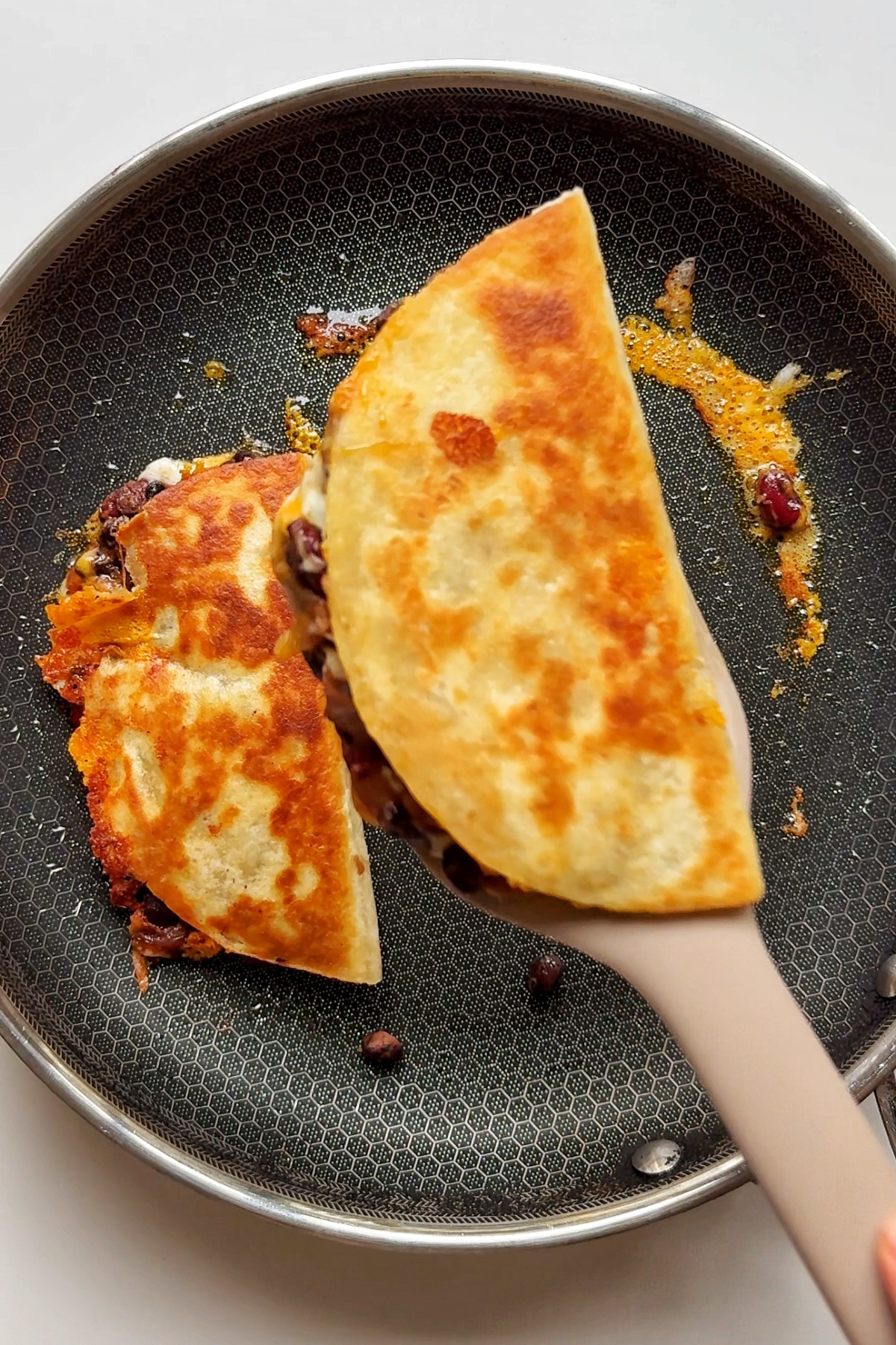 Removing the fried bean tacos from the pan.