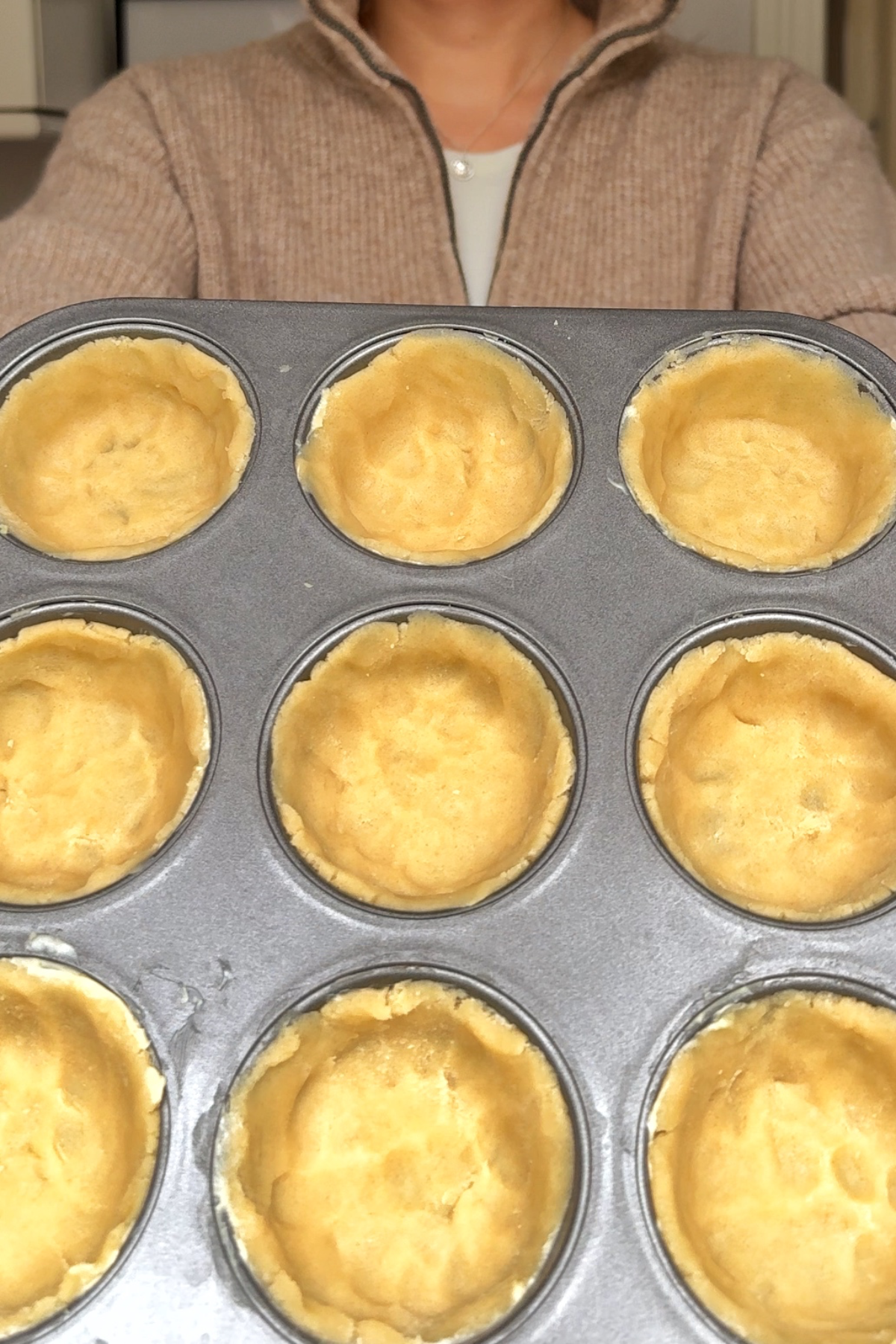 Hand pressing the dough into the cupcake tin.