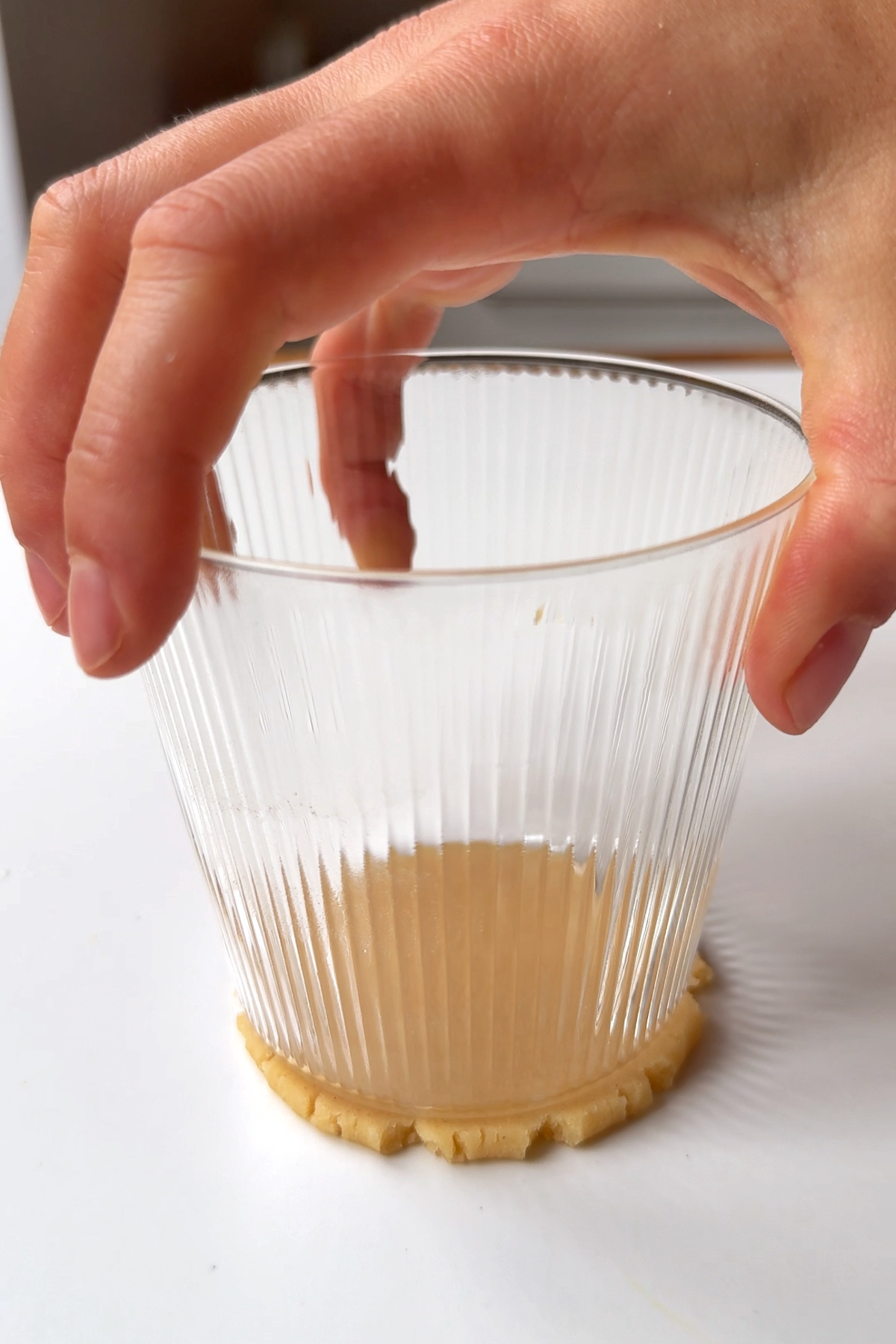 Pressing down the top of the mince pie with the bottom of a glass.