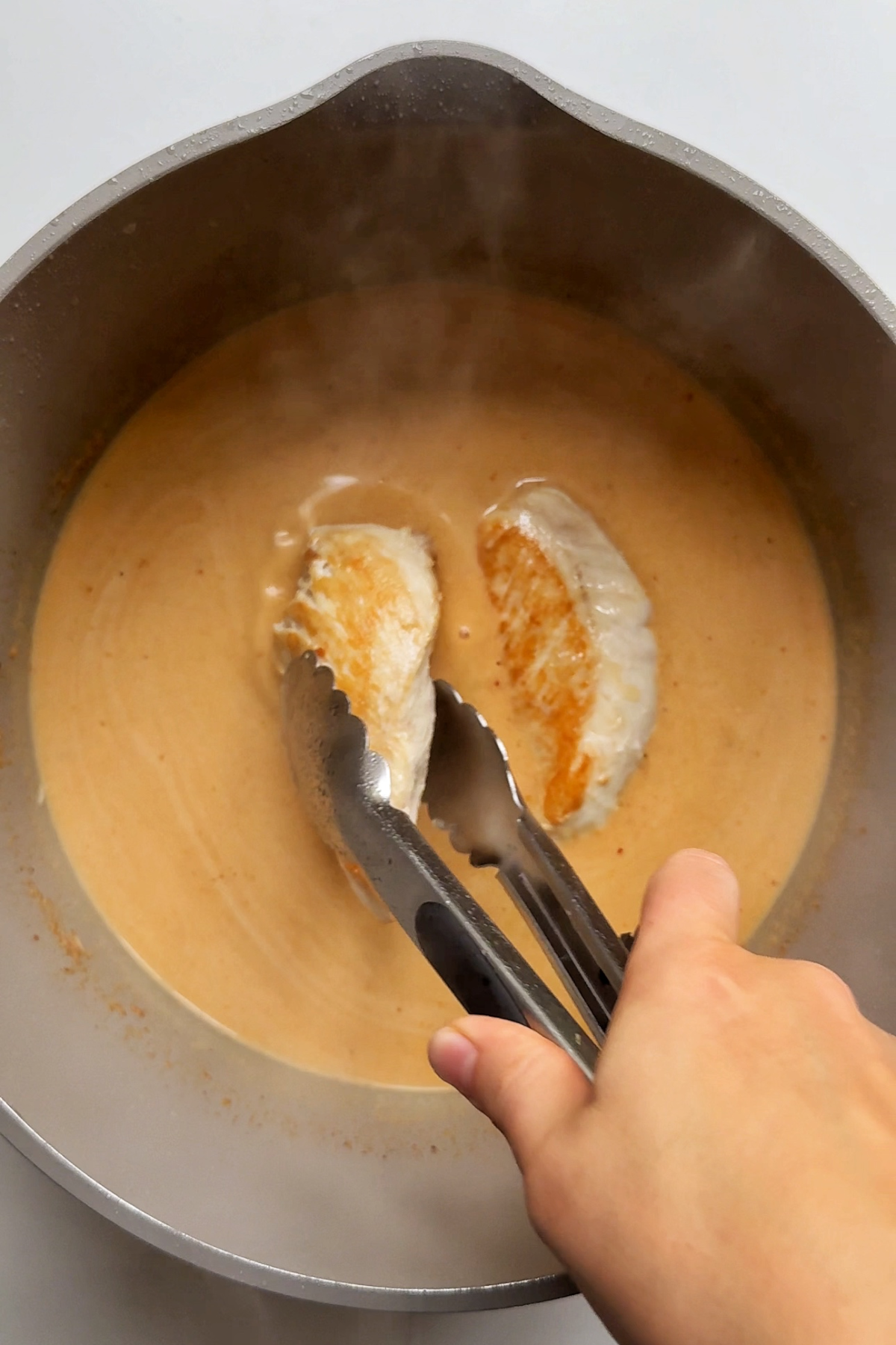 Adding the chicken breast into the spicy peanut butter sauce. 