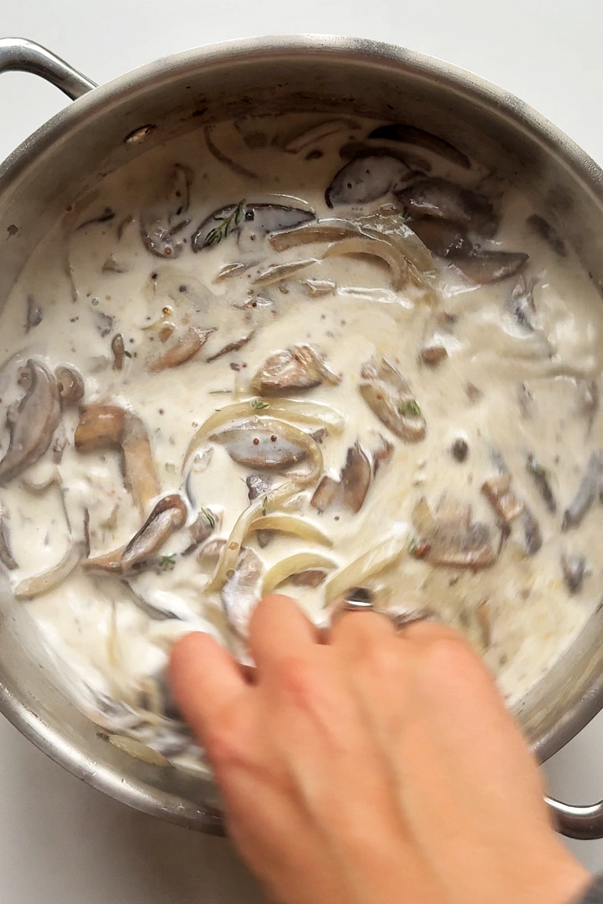 Adding cream to mushroom stroganoff.