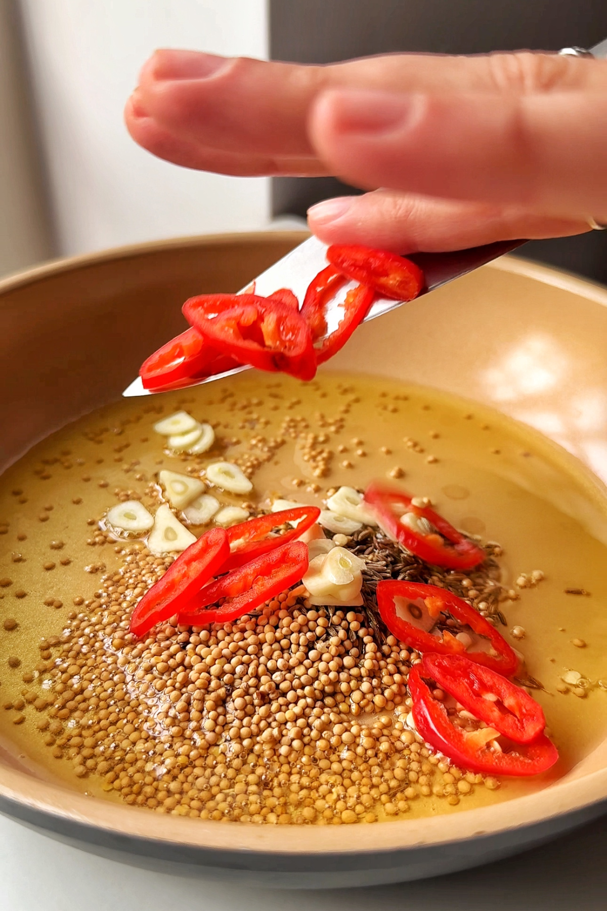 Tempering the spices in a frying pan.