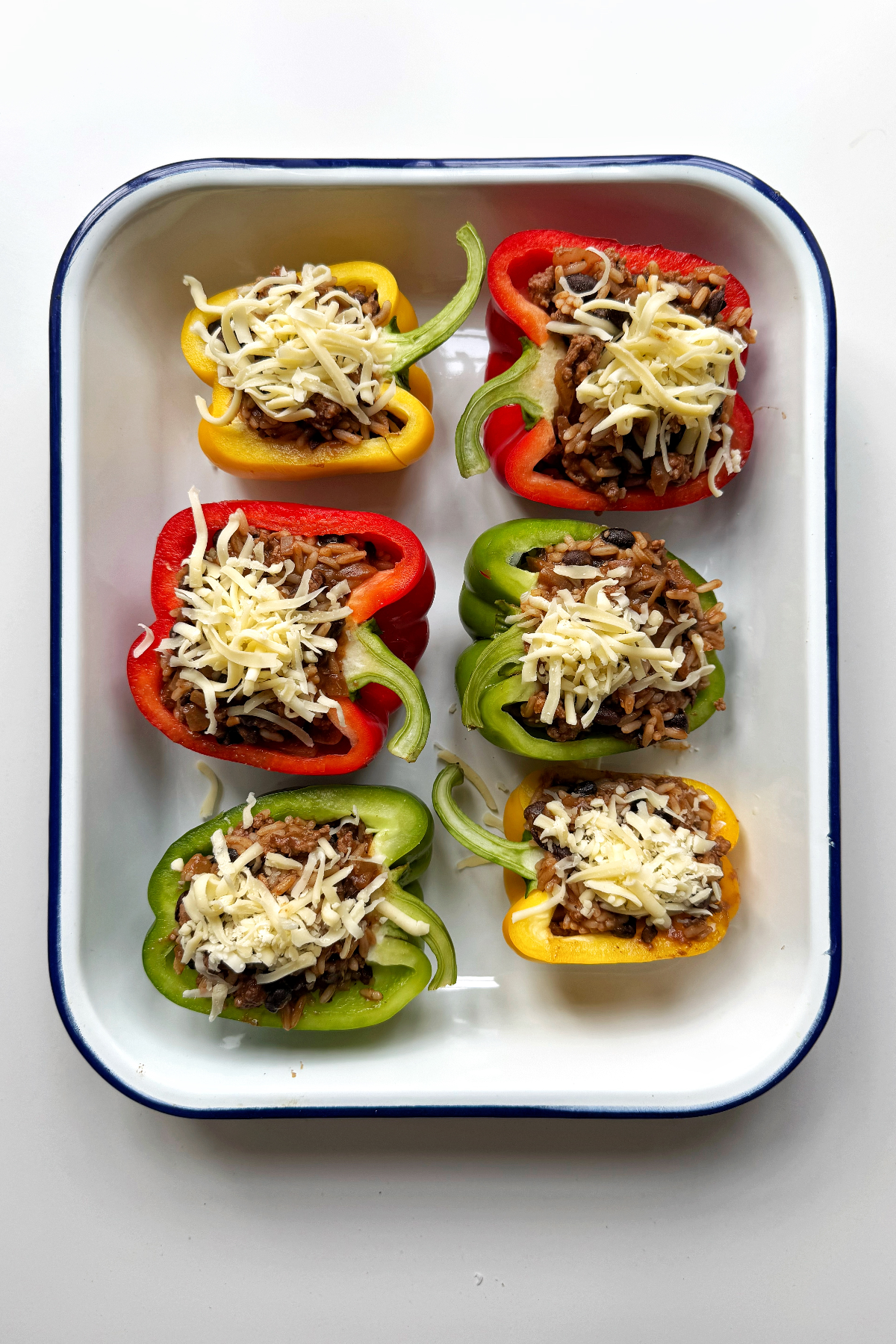Stuffing the bell peppers with the ground beef and rice mixture in a pan.