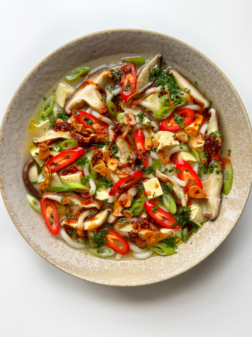 White bowl full of miso soup with mushrooms.