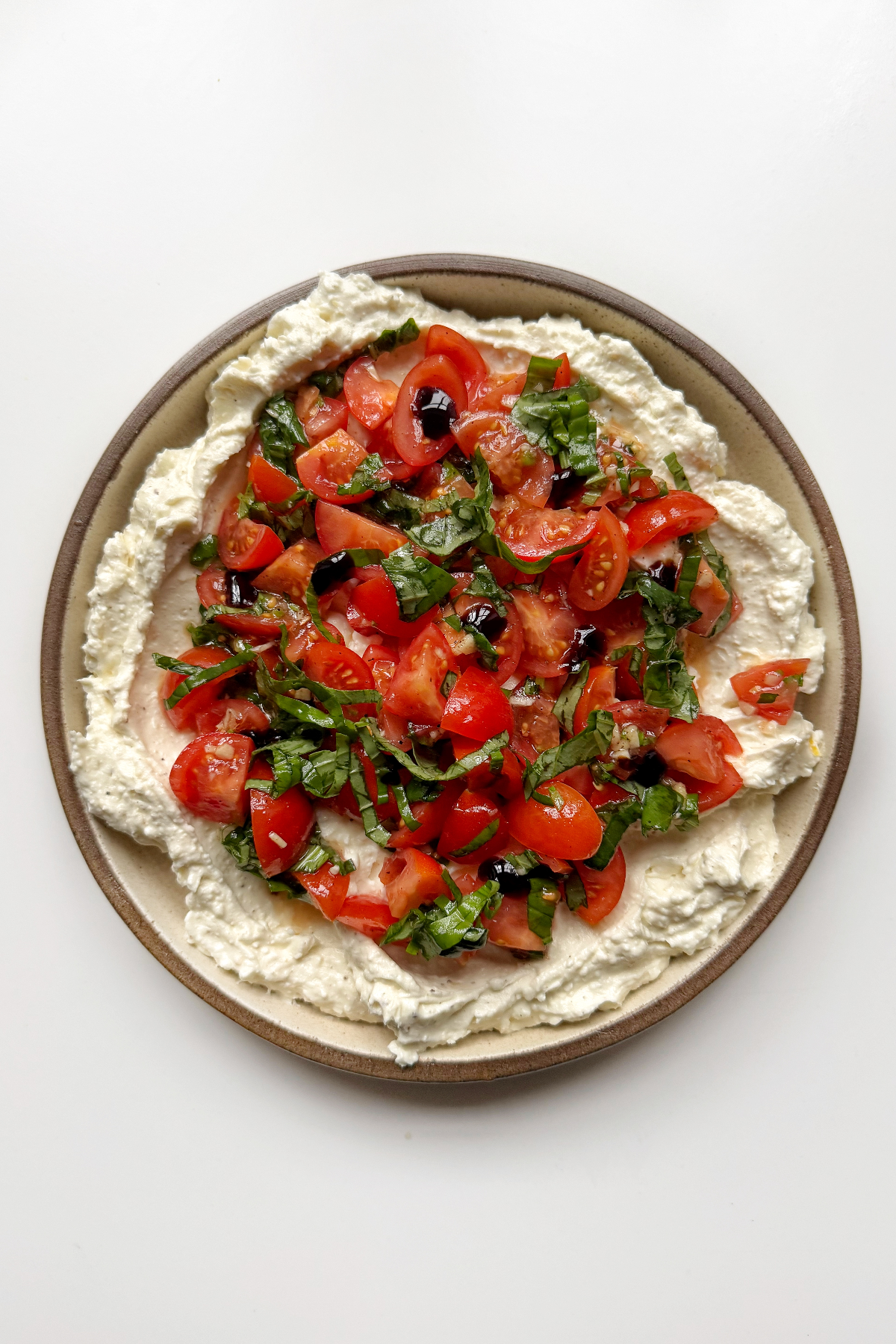 Bruschetta dip on a white and brown plate.