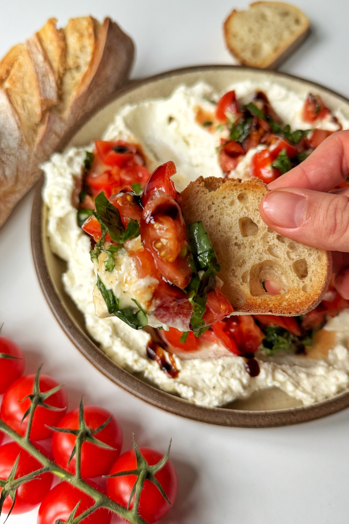 Scooping the bruschetta dip with baguette.